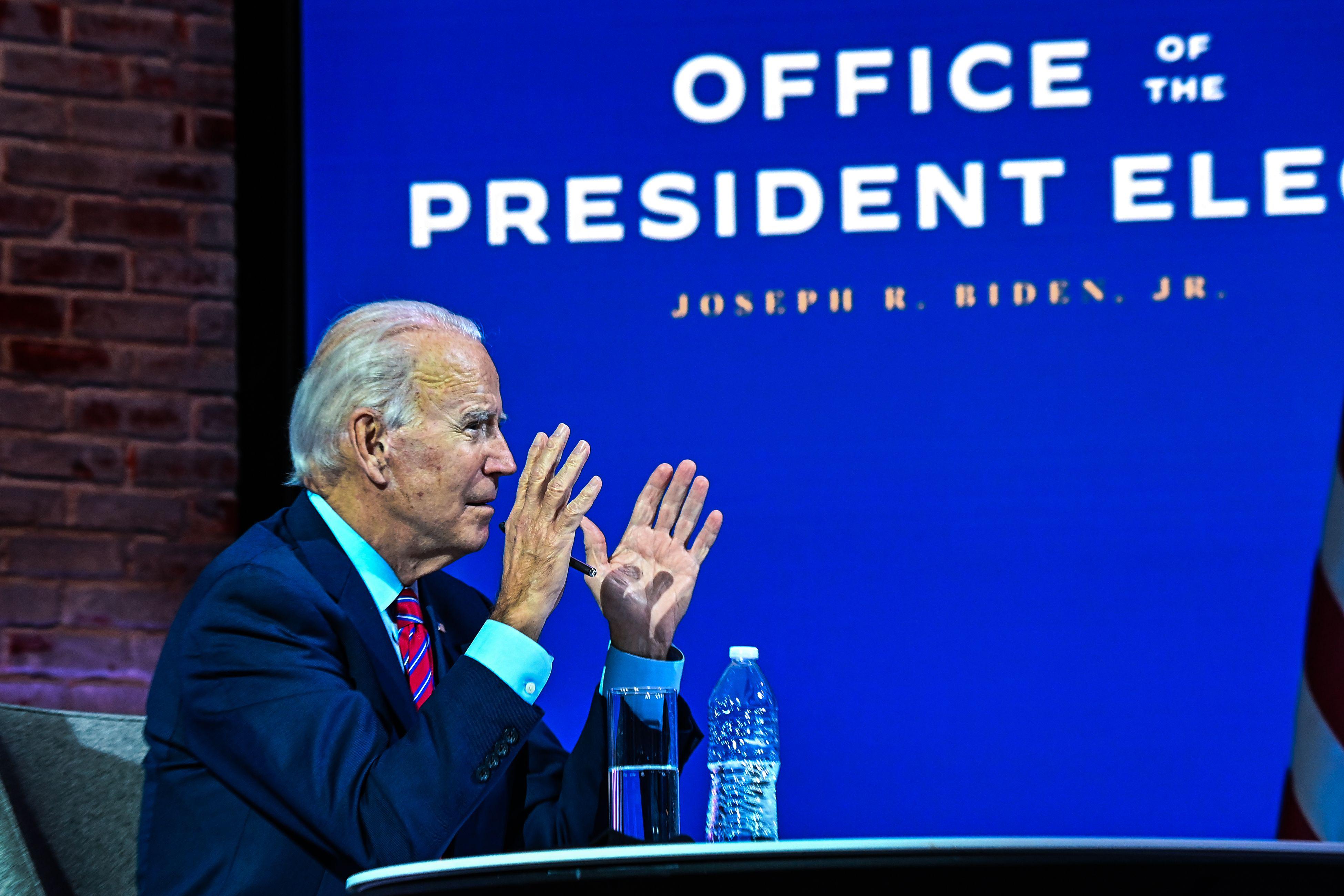 Biden speaks with the Office of the President Elect banner behind him.