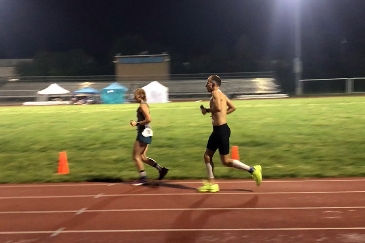 Two runners at the D3 Dawn to Dusk to Dawn ultramarathon in Sharon Hills, Pennsylvania, running at night around a 400-meter track in May 2023. 