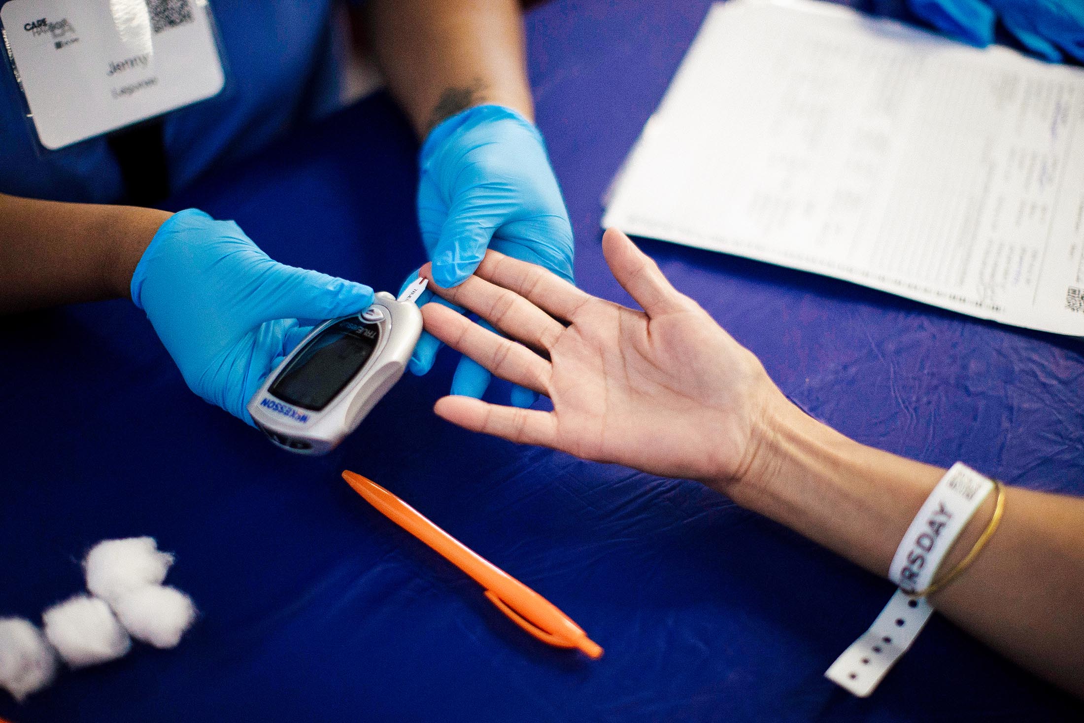 A patient’s finger is poked for a diabetes test.