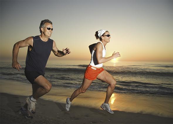 Couple running on beach at sunrise