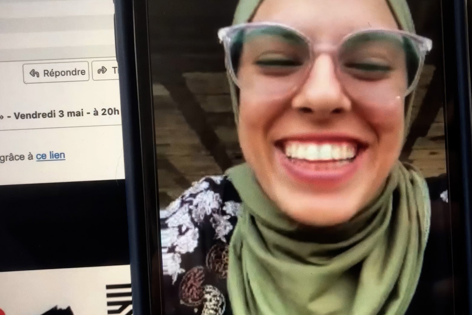 Screenshot of a video call with a young woman smiling, wearing glasses and a green hijab.