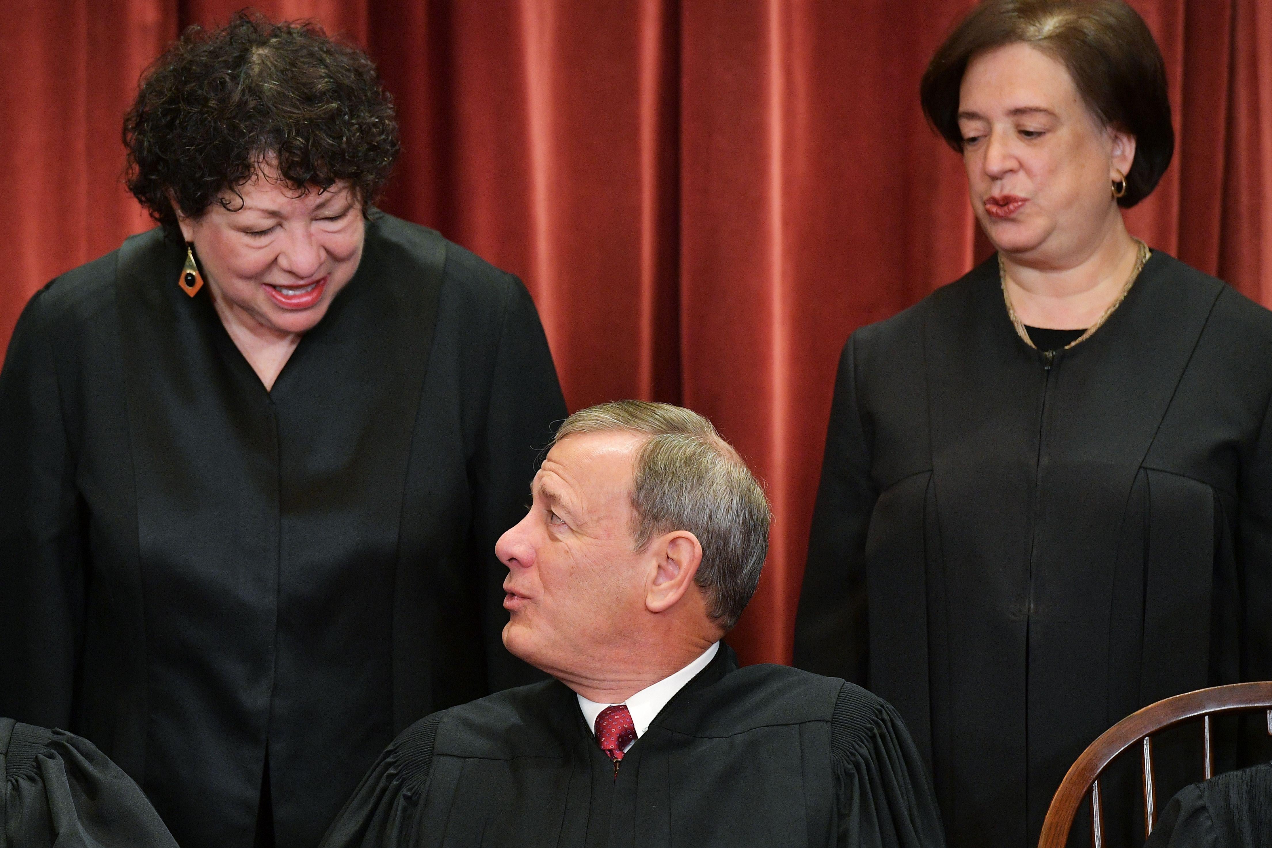 Associate Justice Sonia Sotomayor chats with Chief Justice John Roberts as Associate Justice Elena Kagan looks on while posing for the US Supreme Court official photo at the Supreme Court in Washington, D.C.