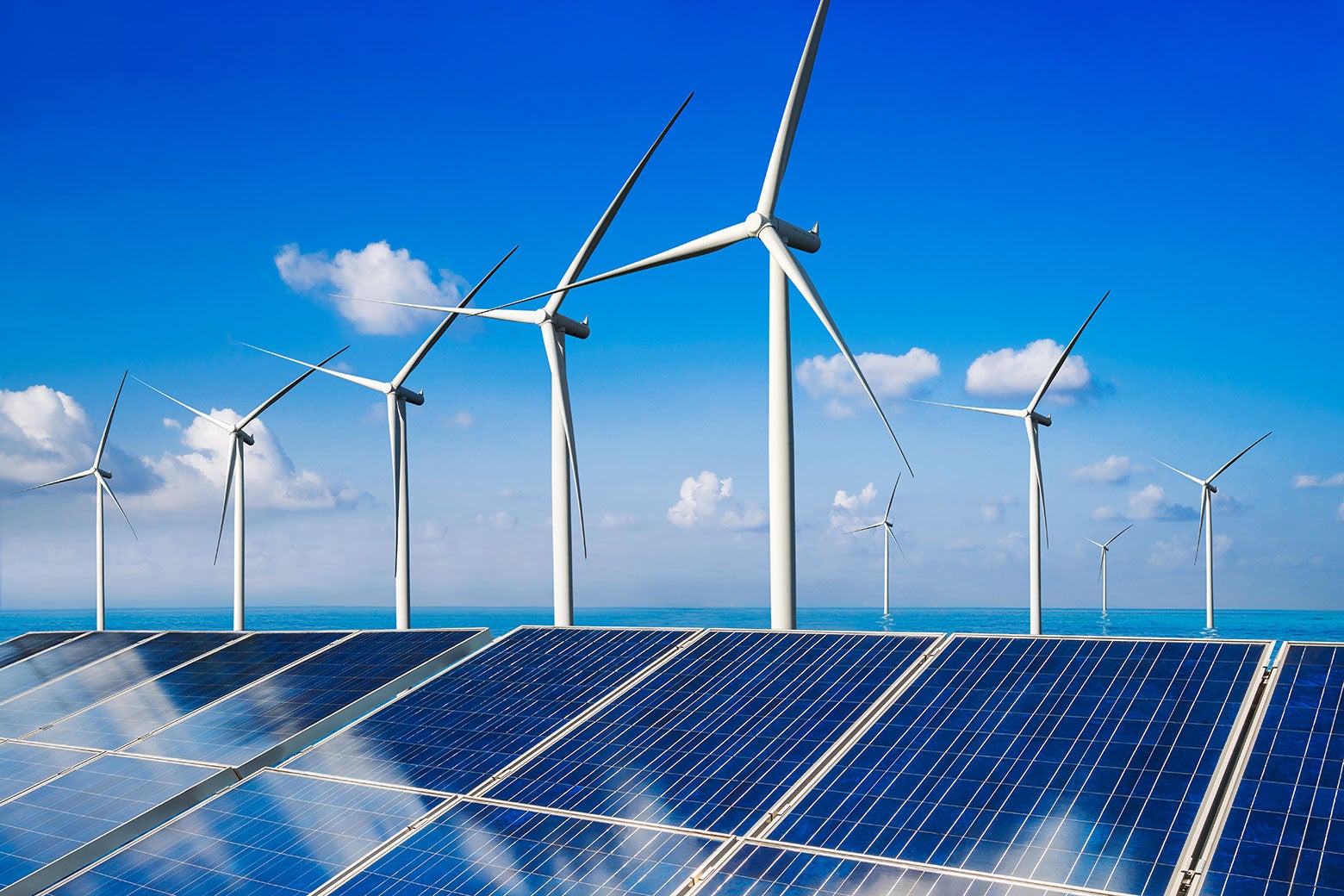 Solar panels and wind turbines against blue sky.