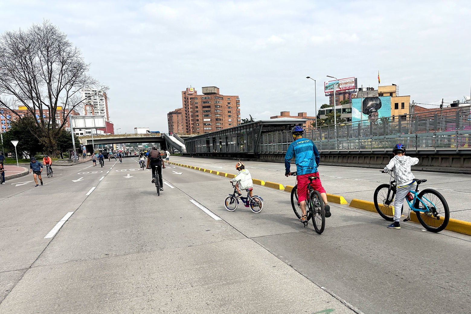 A very young child on a balance bike is among the bikers.