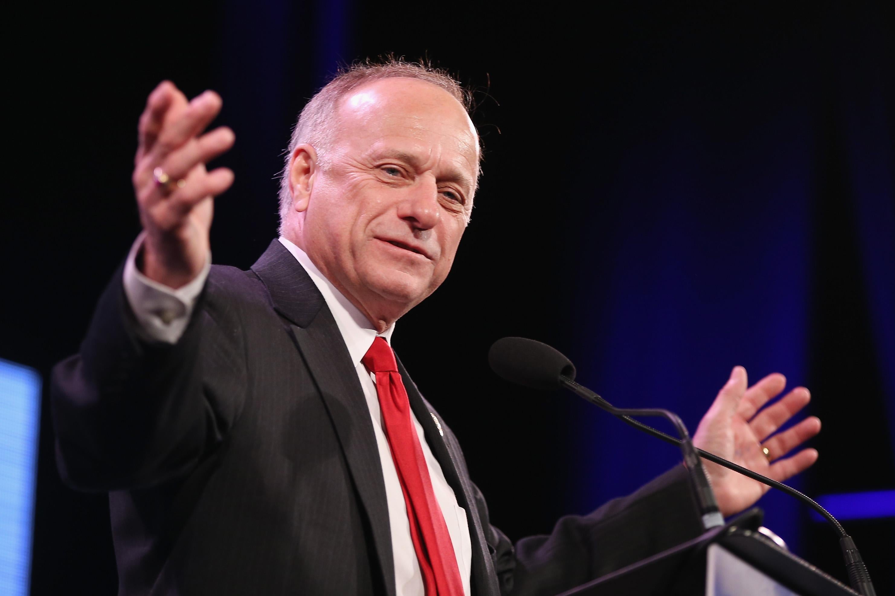 Steve King speaks at a podium, smiling with his arms outstretched.
