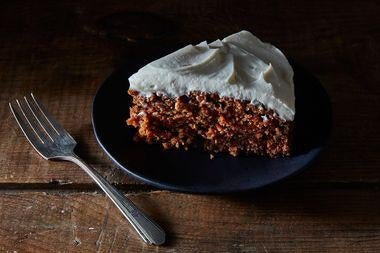 A crumbly brown cake dotted with orange and topped with a thick white frosting.