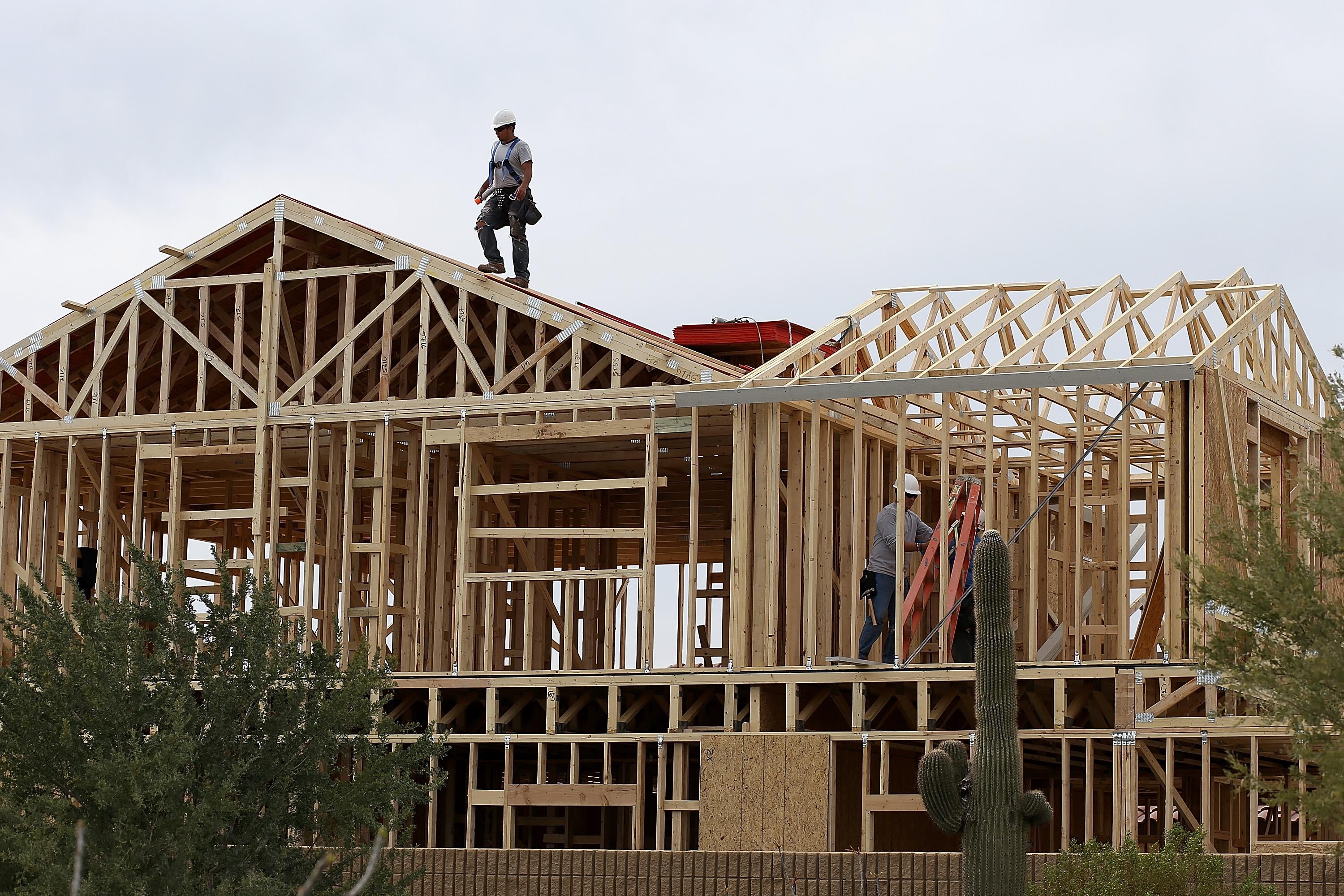 A worker climbs on the roof of a home under construction.