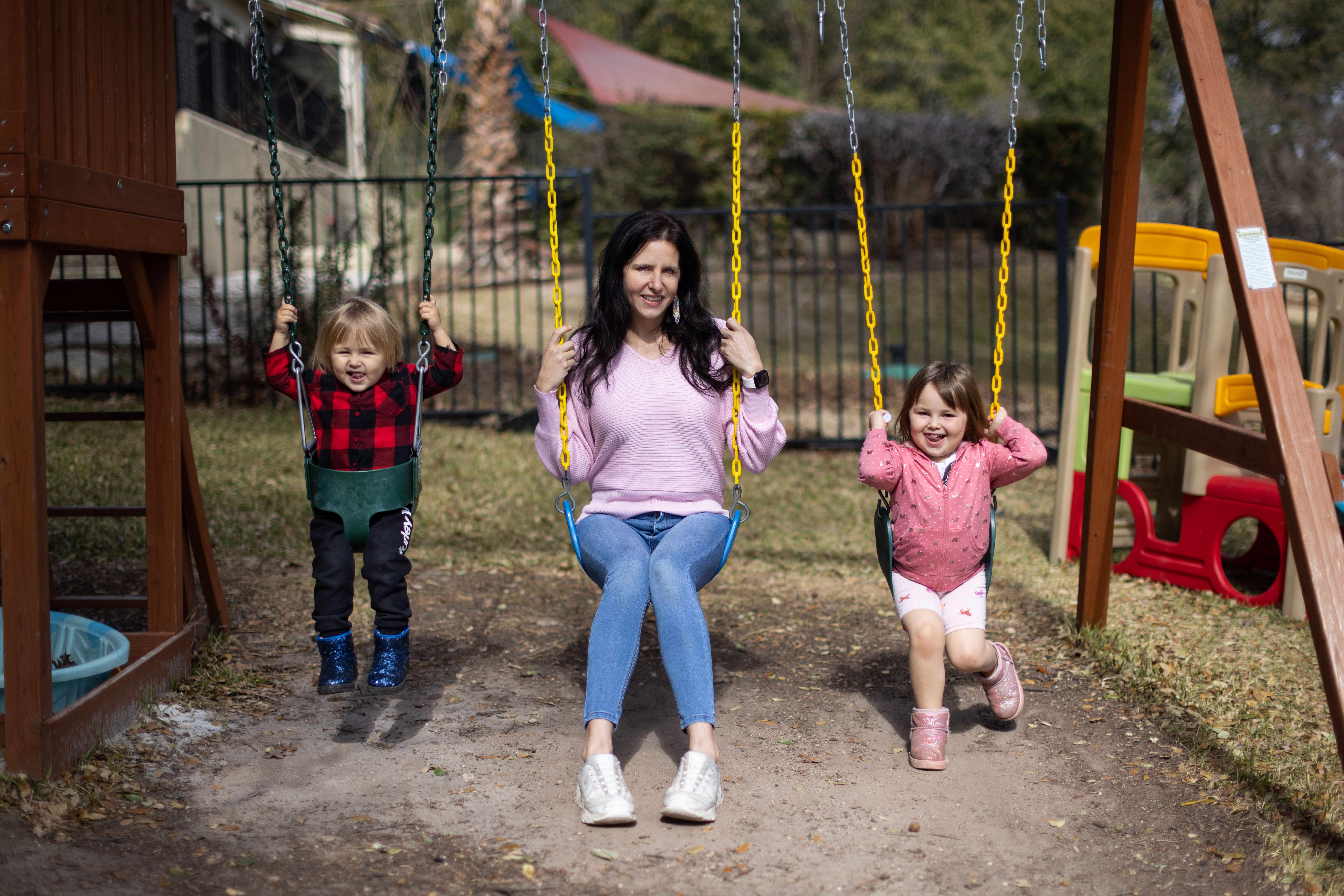 Bianca King with her children on a swing set in her back yard.