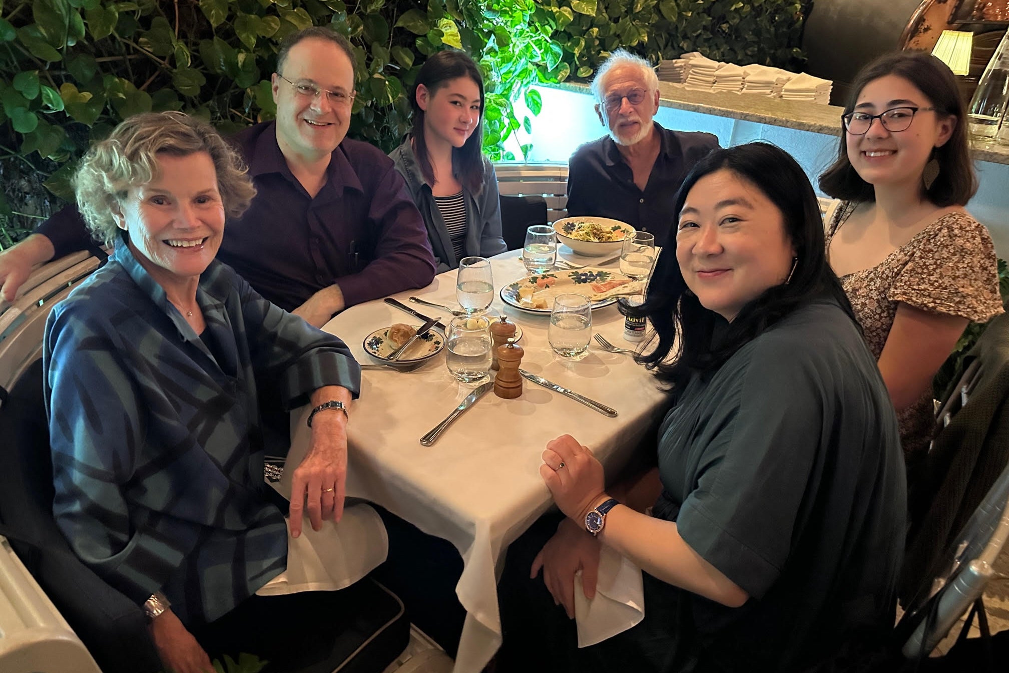 Judy Blume and Lorrie Kim, as well as Kim's husband and daughters and Judy's husband, sitting at a dinner table.