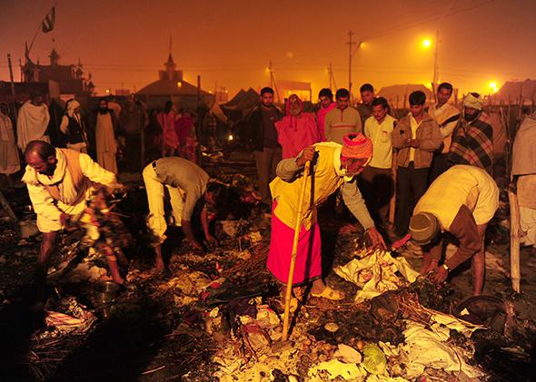 Hindu holy men search for salvageable belongings after a fire destroyed their tents at the Kumbh Mela in Allahabad, India, on Jan. 25, 2013. Nineteen people were injured in the fire, a local report said citing officials.