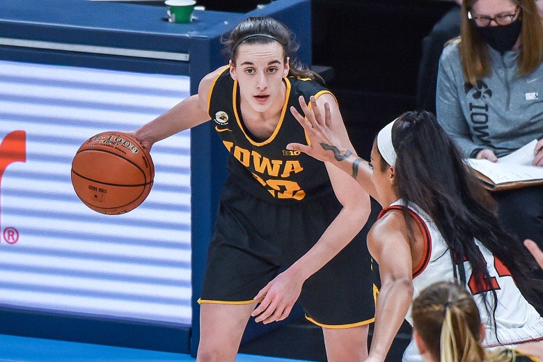 Iowa basketball player Caitlin Clark dribbles with her right hand while an opponent puts a hand in her face.