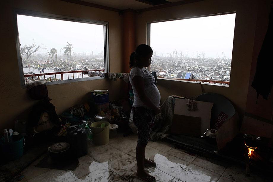 A pregnant woman cooks a meal inside a building overlooking destroyed houses after Super Typhoon Haiyan battered Tacloban city in central Philippines November 10, 2013.