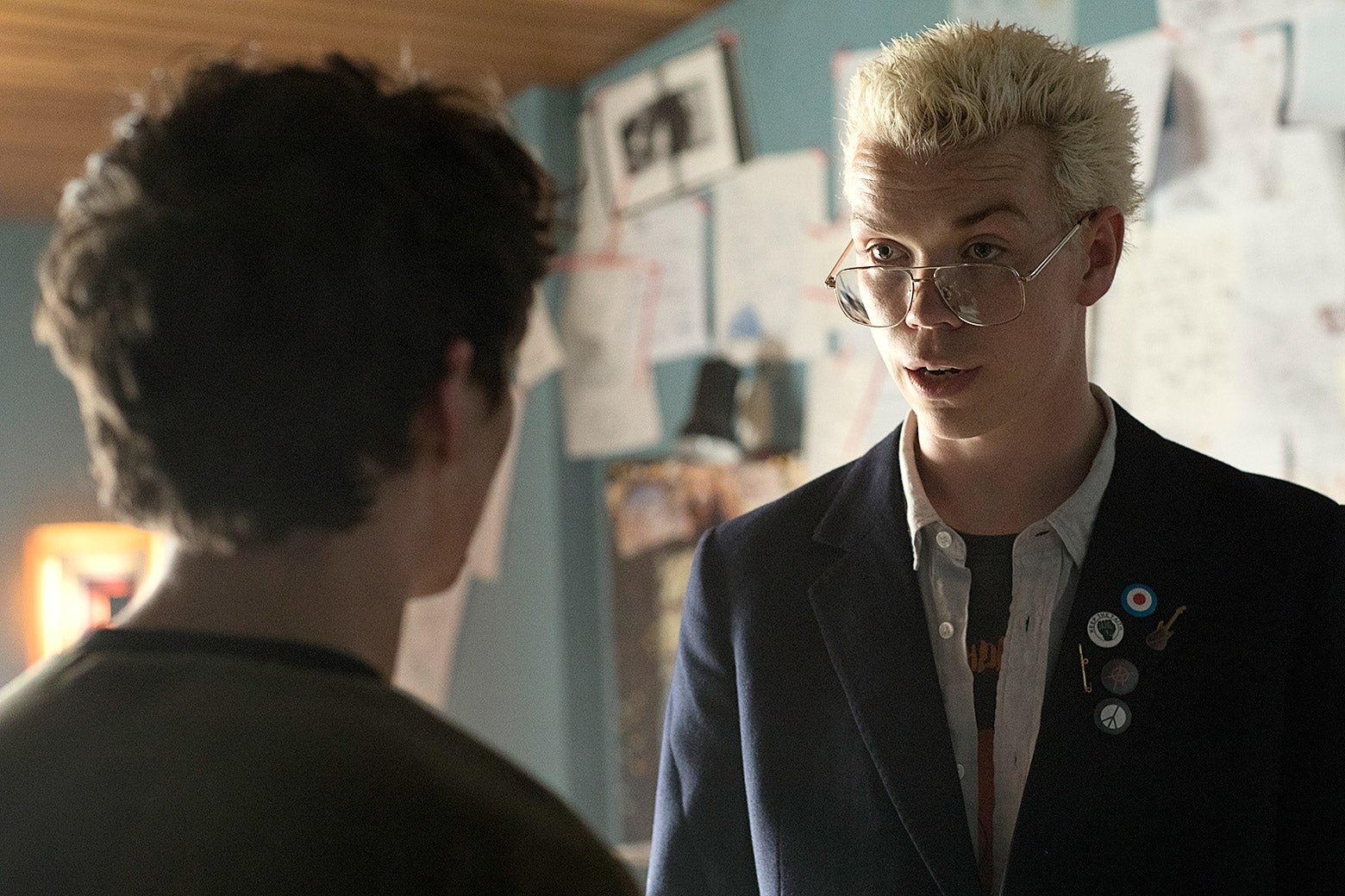 A man speaking to another man with blonde spiked hair and glasses.