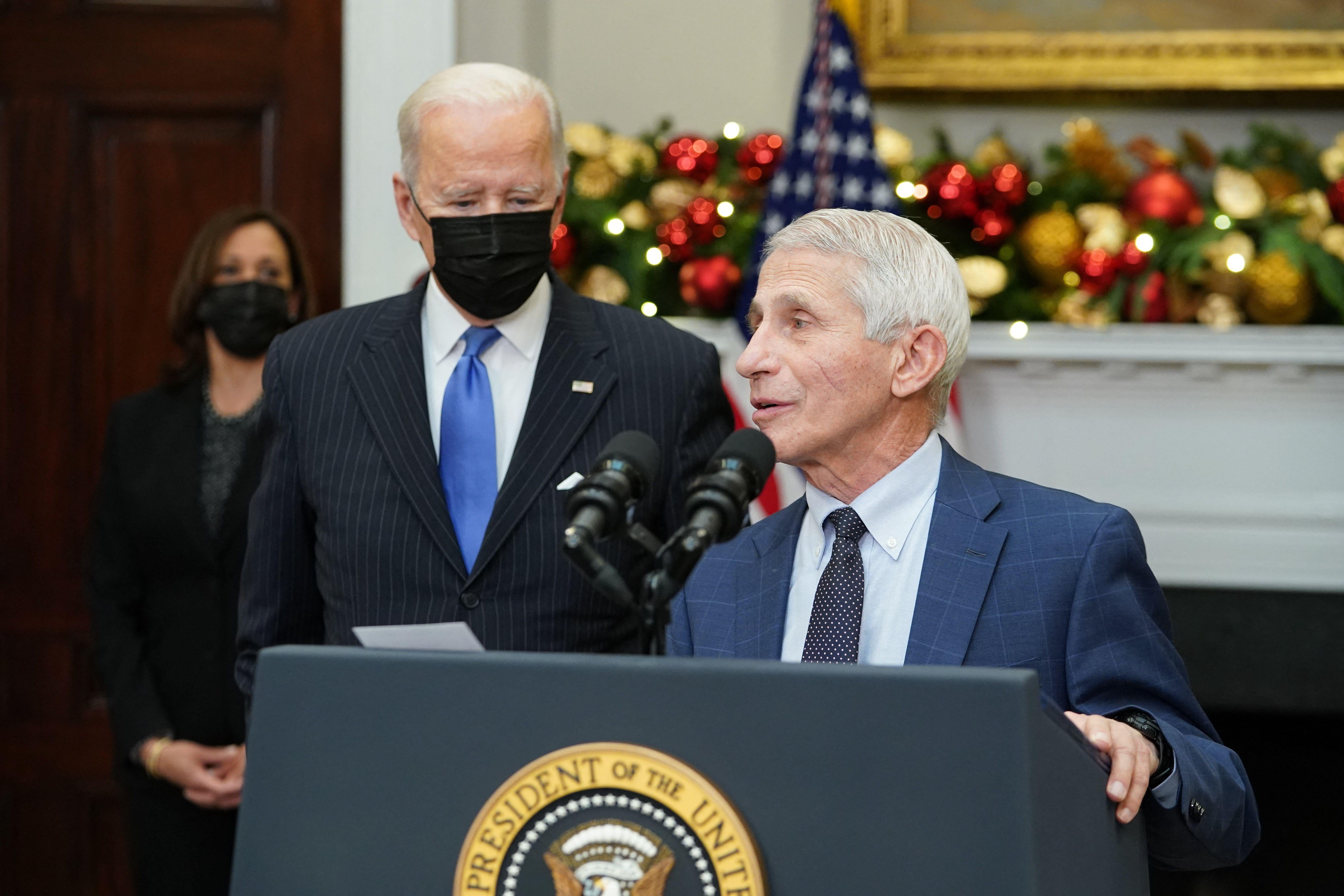 Fauci speaks at a podium with Biden and Harris behind him