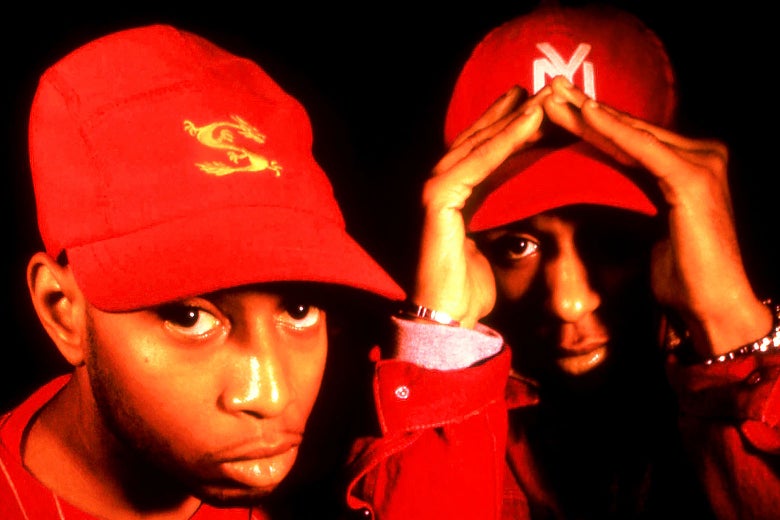 A close-up of both rappers dressed in red with red baseball caps, looking right at the camera