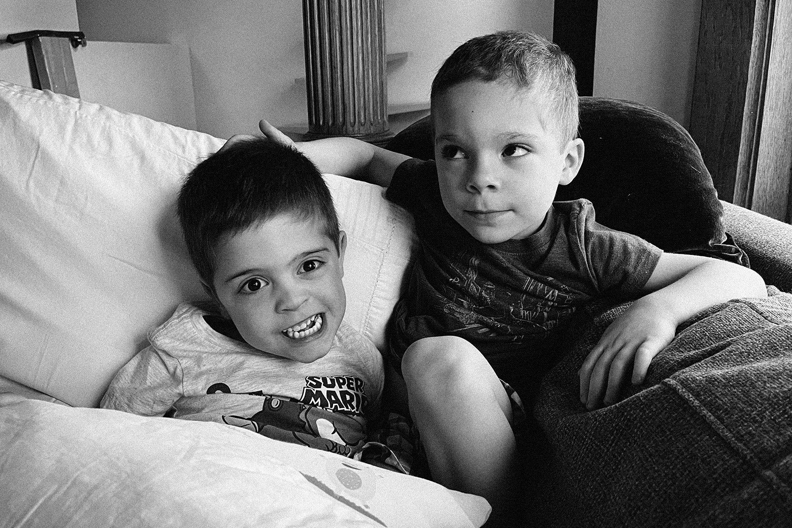 Two young boys play among cushions.