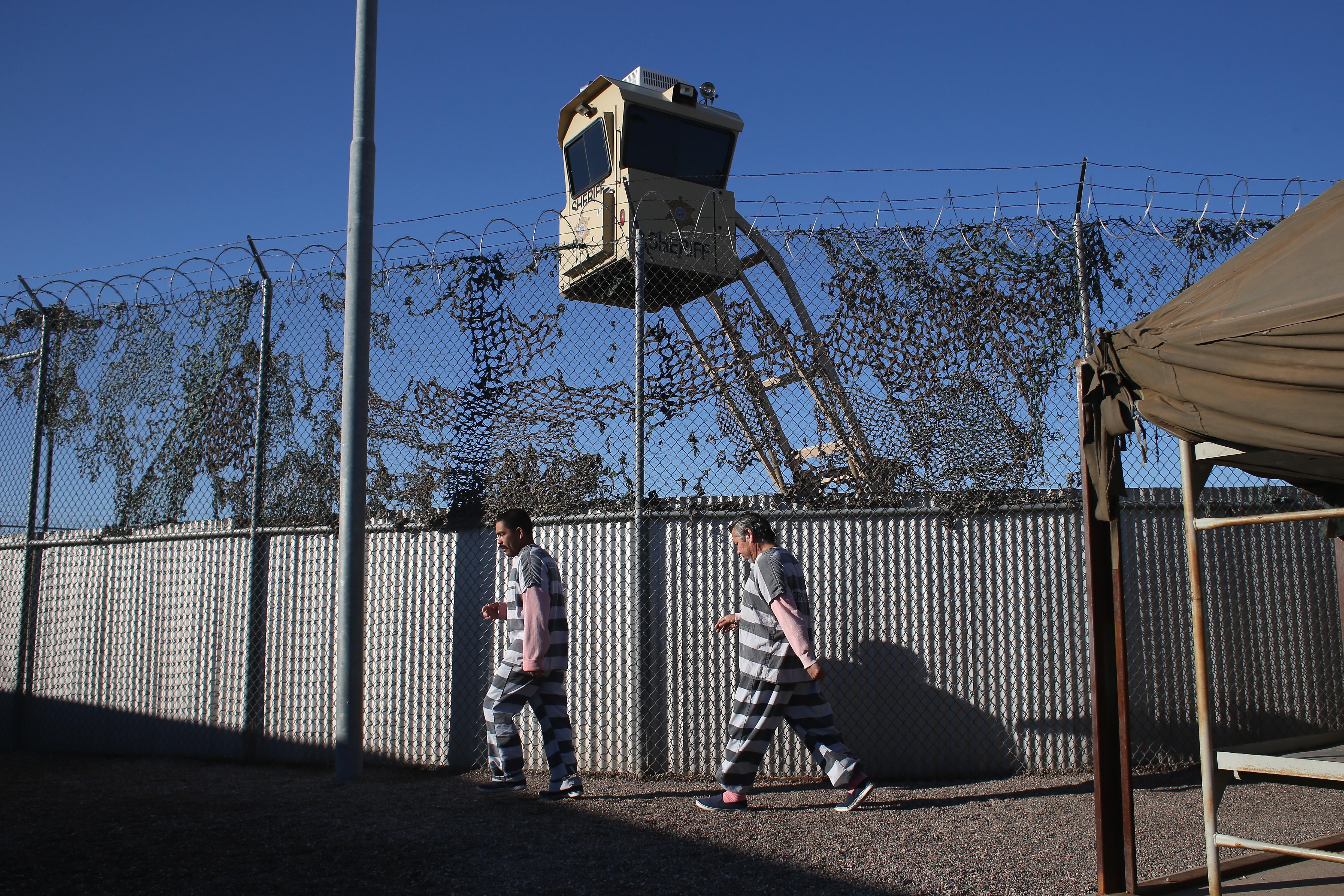 Inmates in striped uniforms walk outside a jail in Arizona