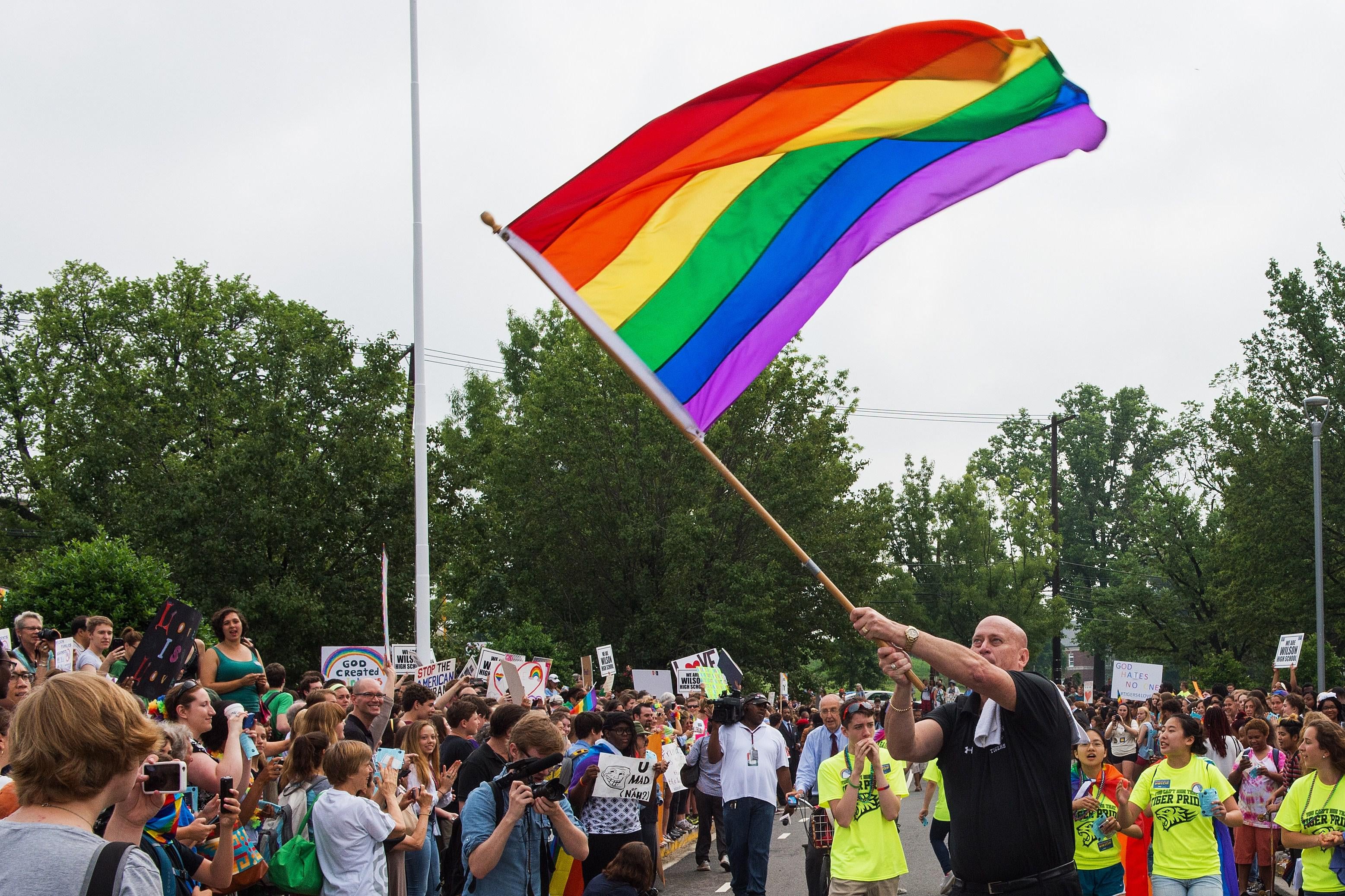 Principal Pete Cahall, waves a rainbow flag, symbolizing gay pride, at a rally of about 1000 Woodrow Wilson High School students and gay supporters June 9, 2014 at Woodrow Wilson High School in Washington, DC. The rally was held to counter a planned protest by  Westboro Baptist Church, the Kansas-based organization known for anti-gay picketing at funerals.      AFP PHOTO/Paul J. Richards        (Photo credit should read PAUL J. RICHARDS/AFP/Getty Images)
