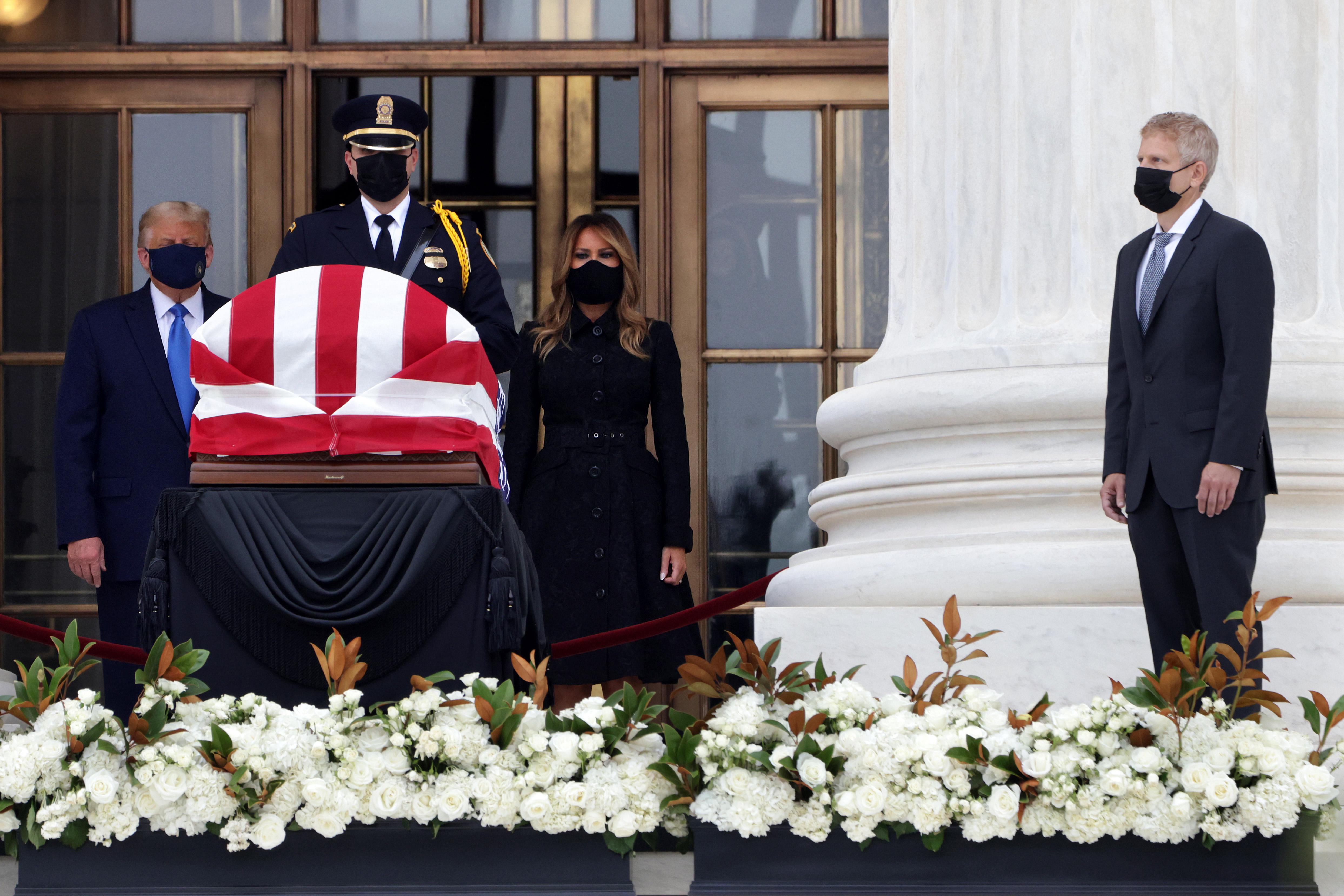 Donald and Melania Trump stand in front of Ruth Bader Ginsburg's casket in the entryway of the Supreme Court while Neil Seigel stands by.