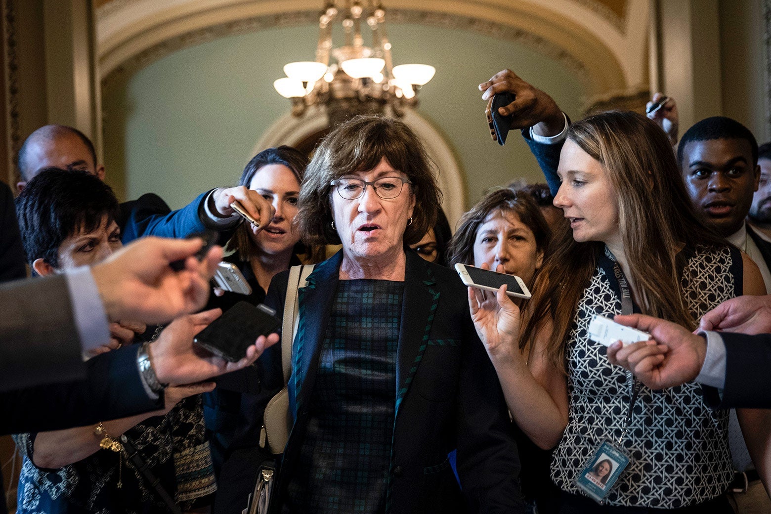 Susan Collins surrounded by reporters.