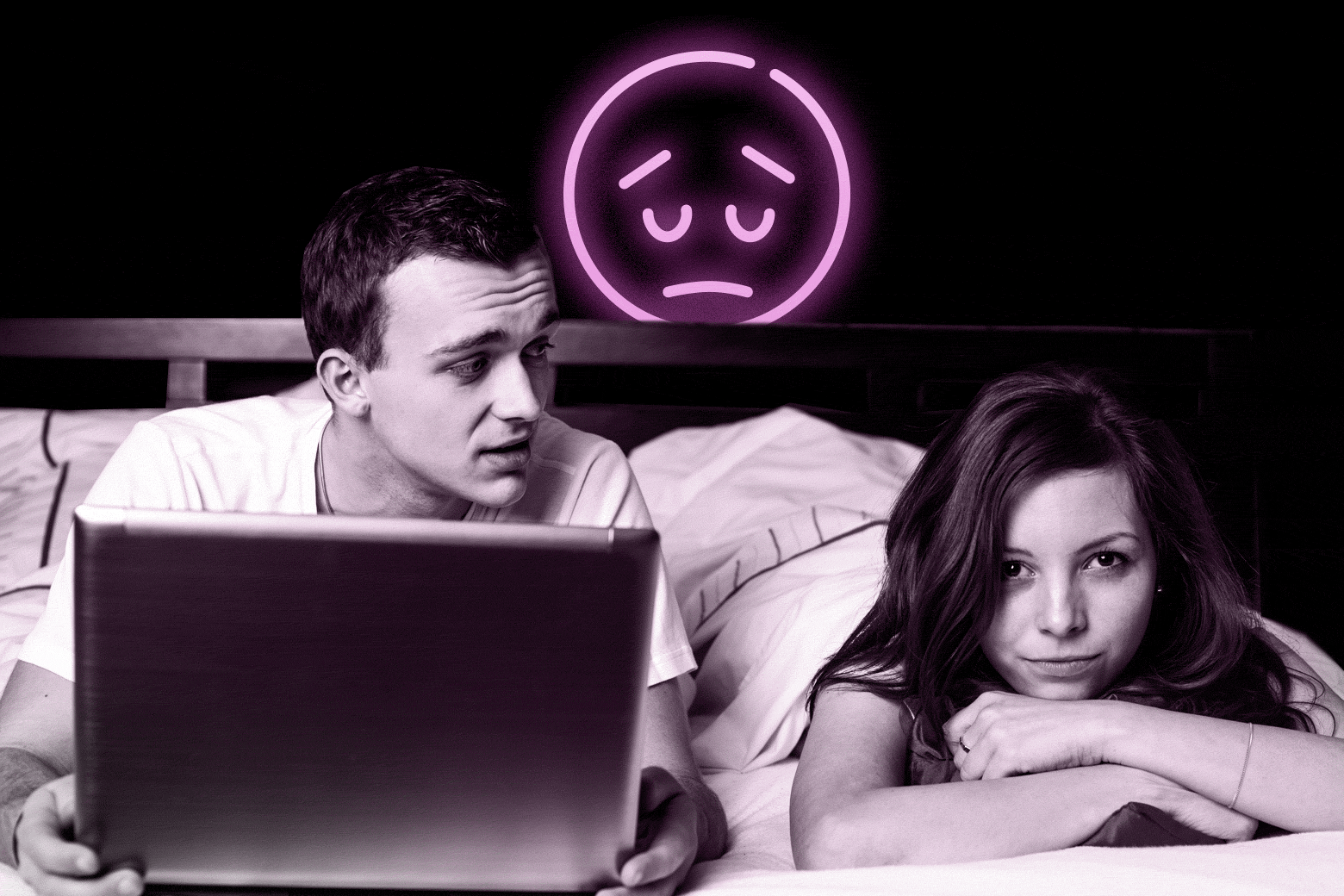 A man reads from a laptop in bed with a woman beside him looking miserable. A sad face emoji in neon hovers over them.