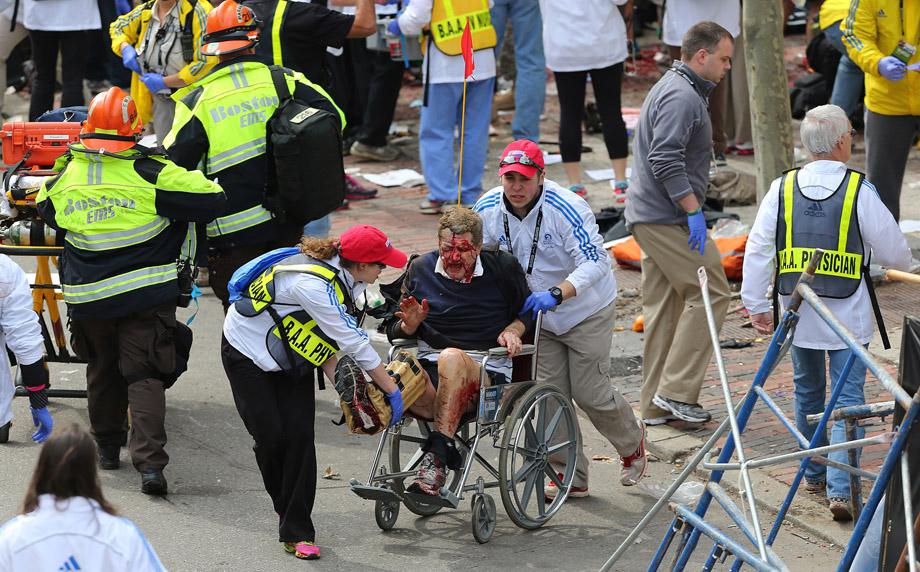 A person who was injured in an explosion near the finish line of the 117th Boston Marathon is taken away from the scene in a wheelchair.