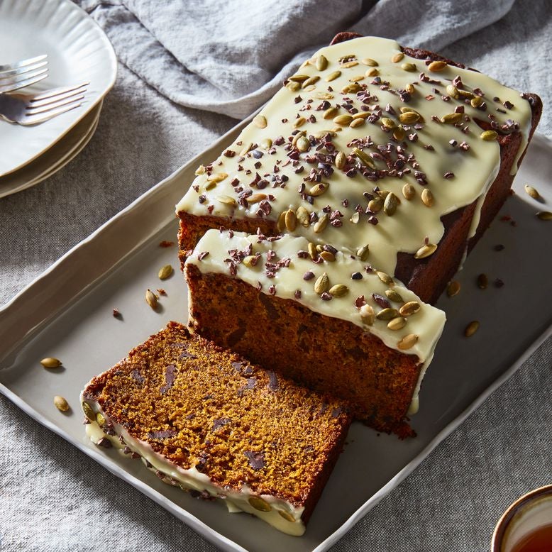 Pumpkin bread loaf with pumpkin seed–studded glaze, sliced on a tray to reveal dark chocolate pieces on the inside