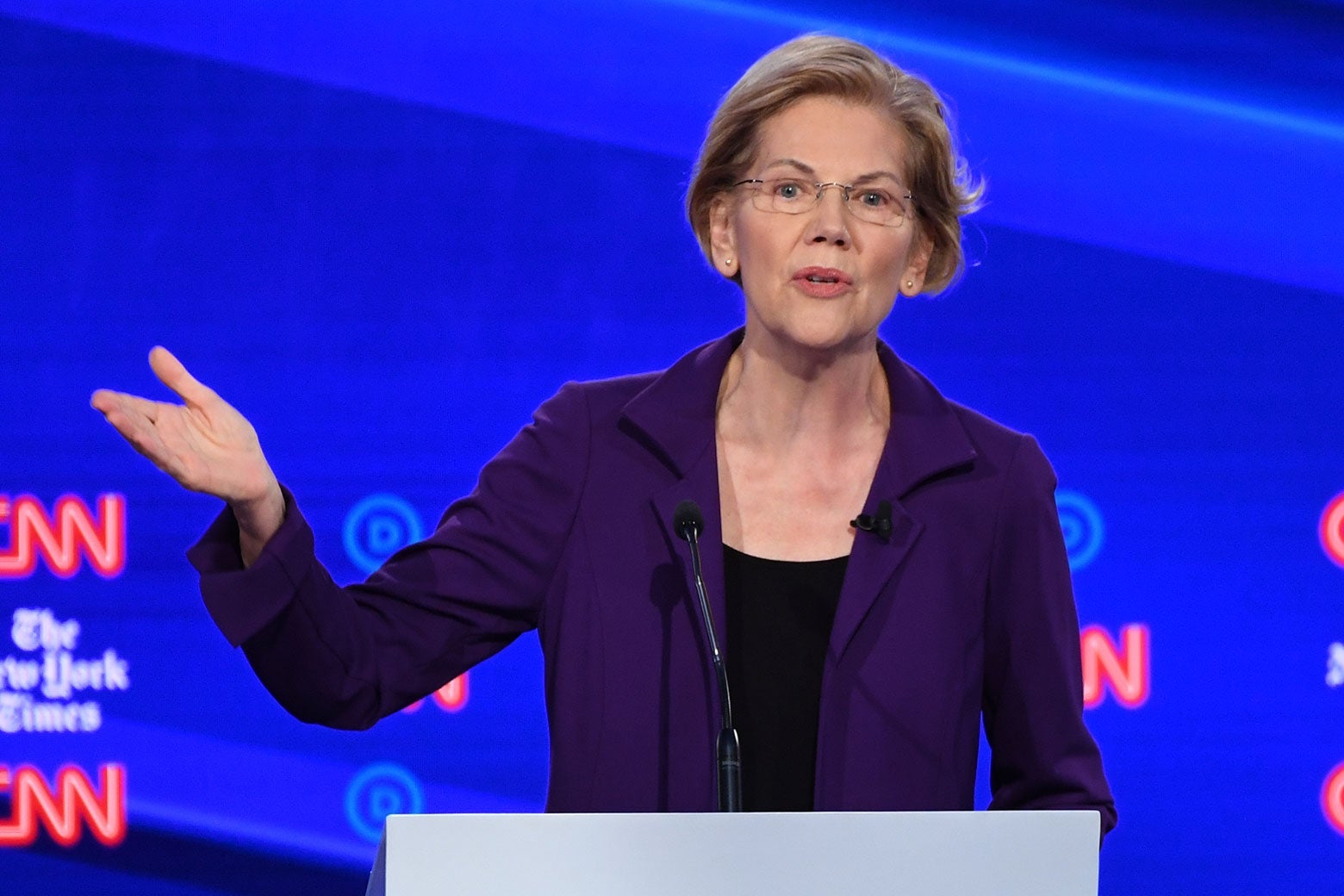 Warren gesturing at a podium.