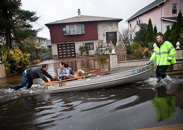 An emergency responder helps evacuate two people with a boat, after their neighborhood experienced flooding due to Hurricane Sandy, on October 30, 2012, in Little Ferry, New Jersey.