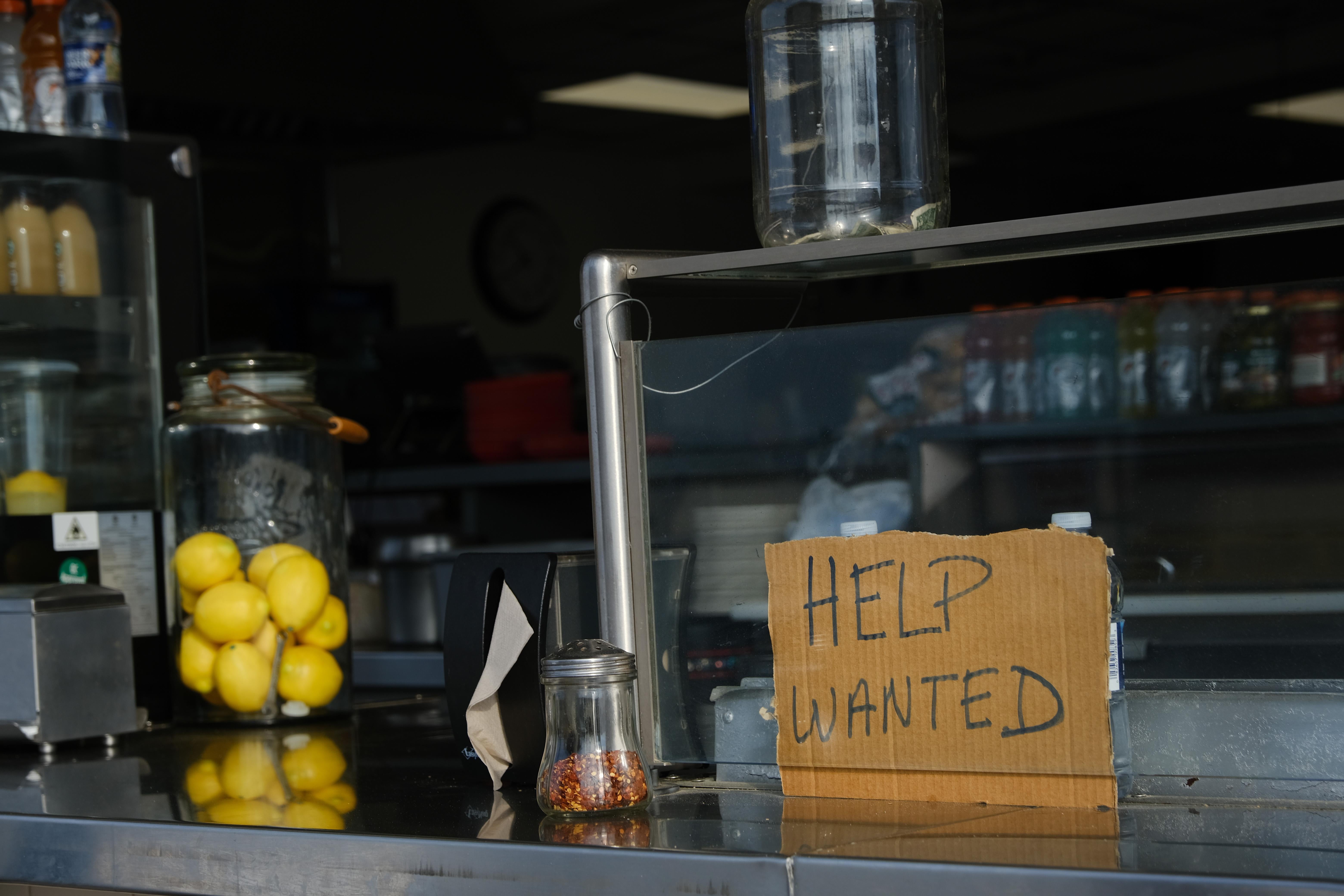 A cardboard "help wanted" sign on a counter inside a boardwalk restaurant in Wildwood, New Jersey