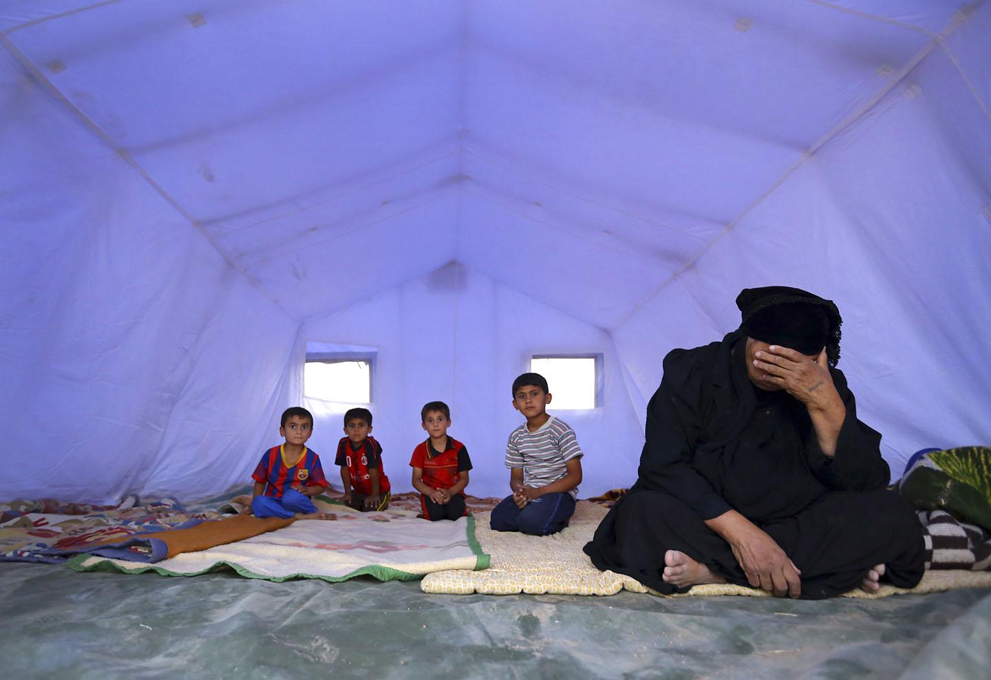 A family, who fled from the violence in Mosul, sits inside a tent at a camp on the outskirts of Erbil in Iraq's Kurdistan region, June 12, 2014. 