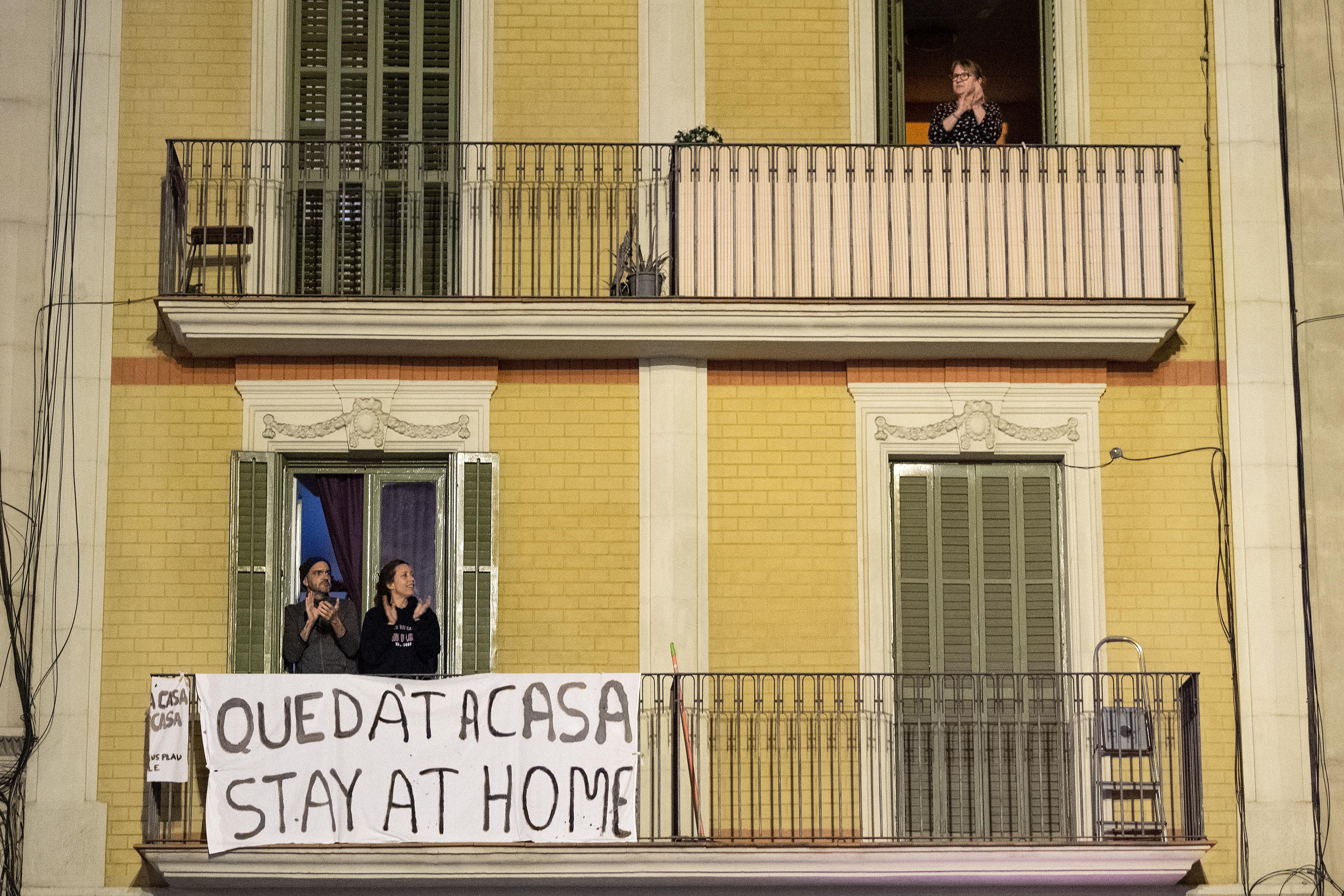 people on a balcony with a sign that says "stay home"