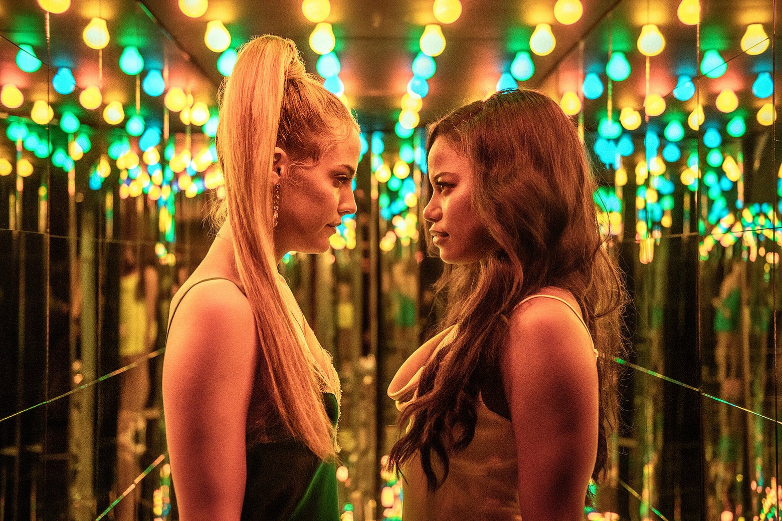 Taylour Paige and Riley Keough looking into each others eyes.
