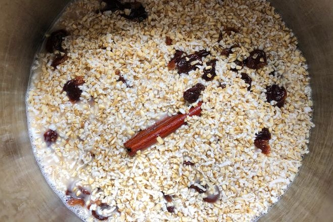 Oats and cinnamon soaking in a stainless steel bowl.