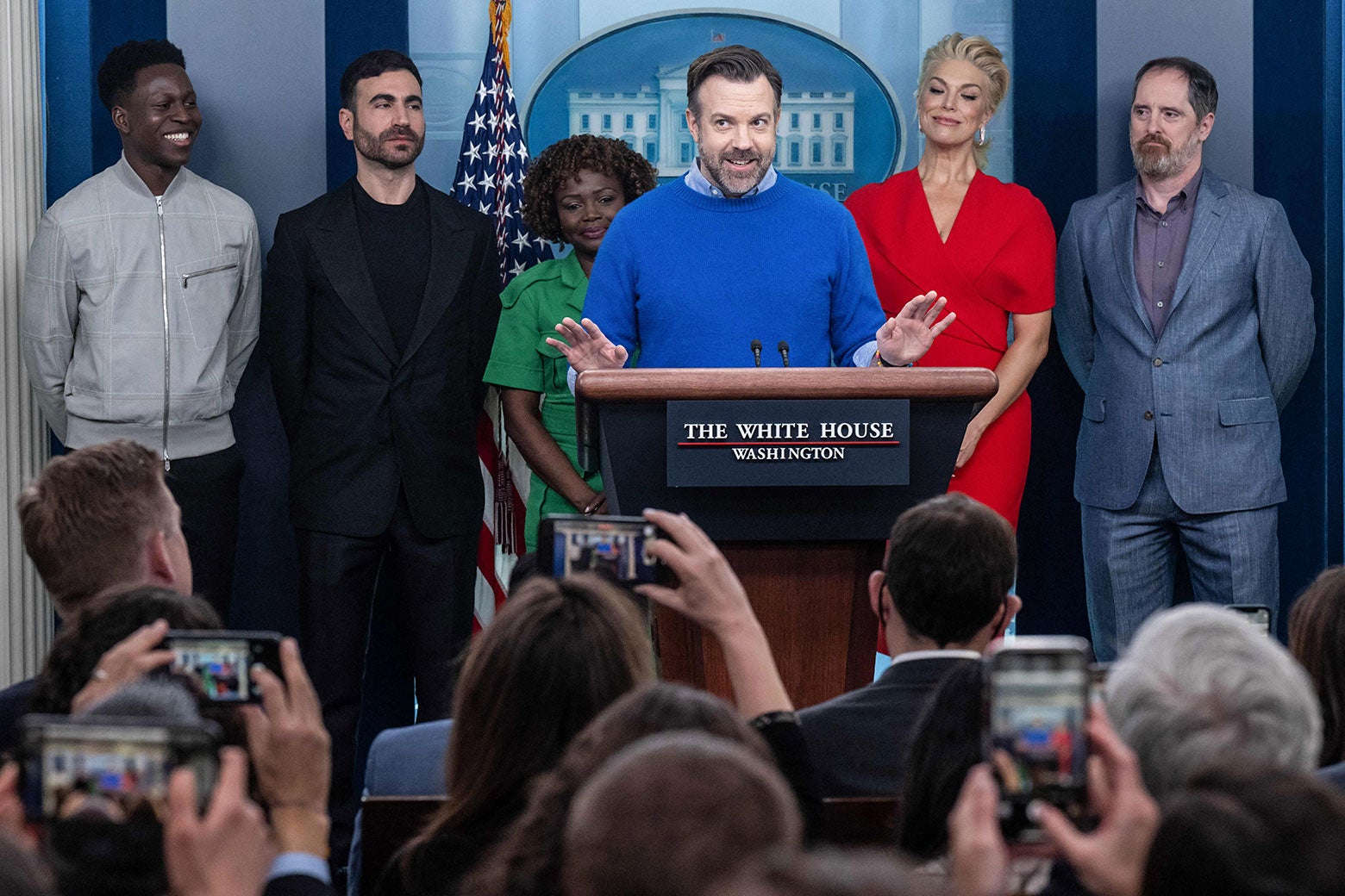 The cast of Ted Lasso with the press secretary at the podium in the White House briefing room.