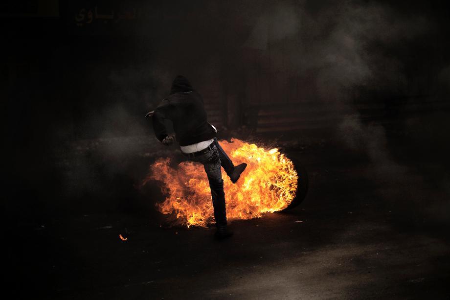 A Palestinian demonstrator kicks a flaming tire during clashes with the Israeli army in the West Bank city of Hebron on April 3, 2013.
