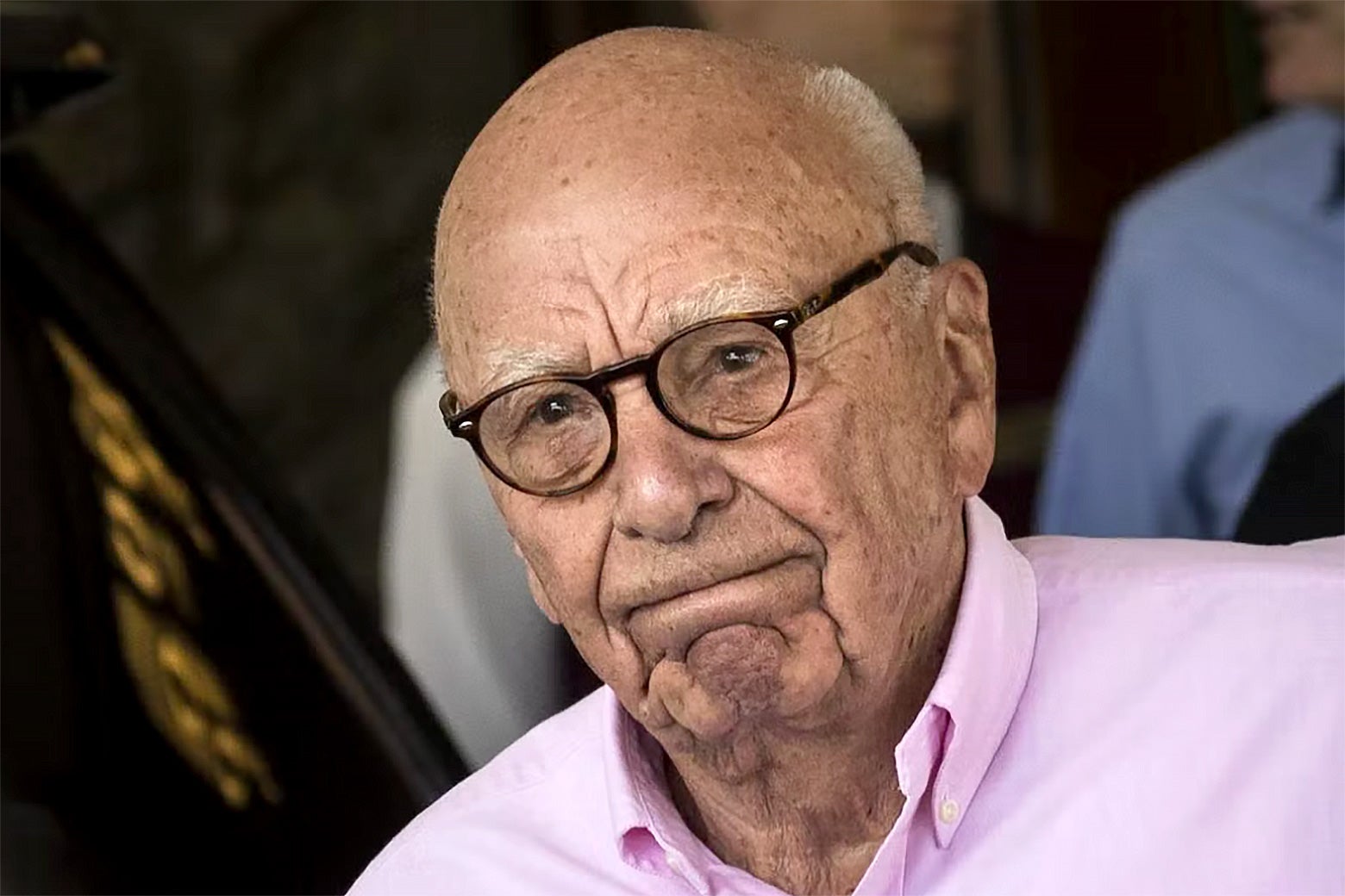 Rupert Murdoch with a serious expression on his face wearing a light blue Polo button down shirt.