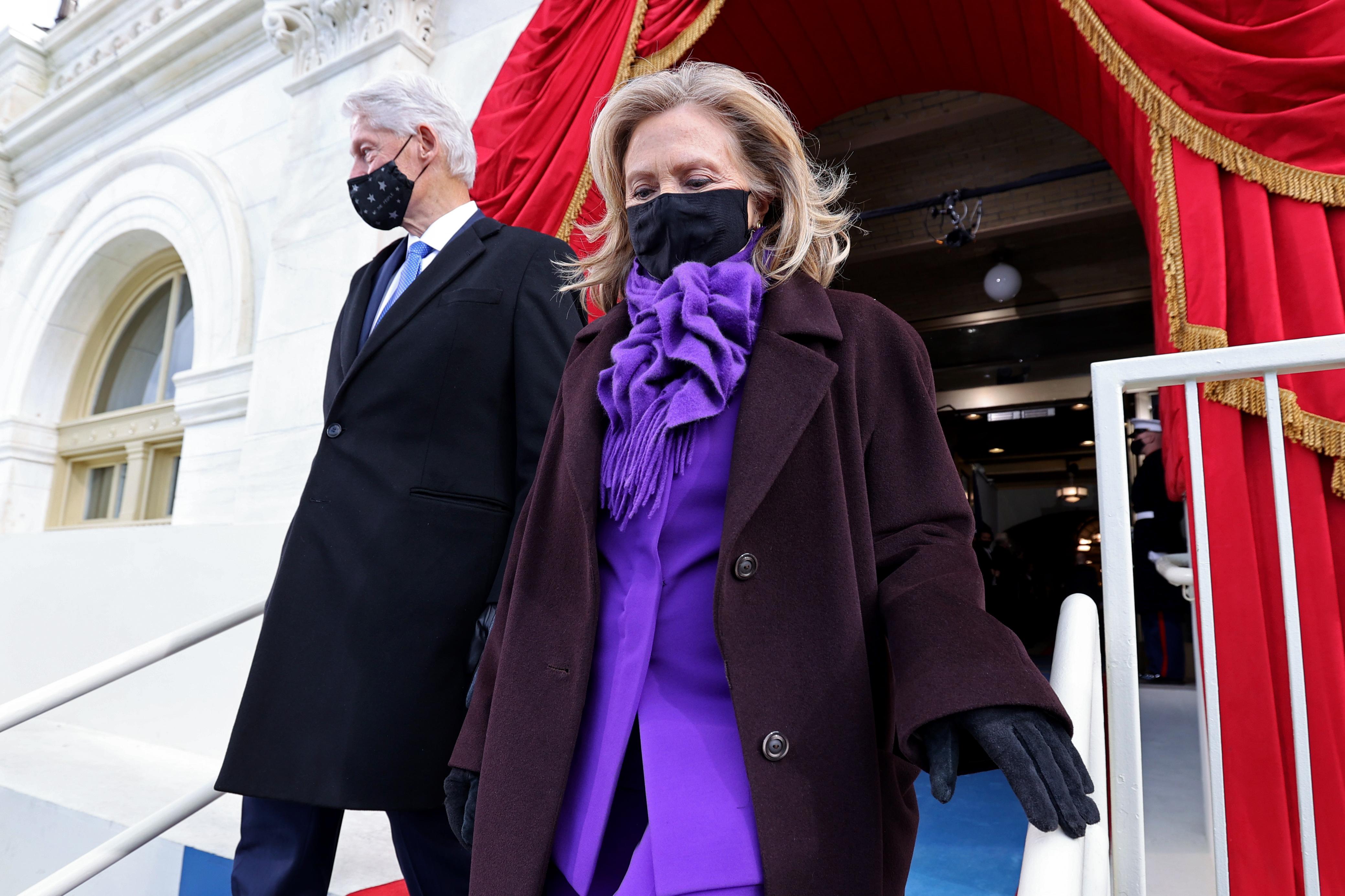 Bill and Hillary Clinton arrive. Hillary is wearing a purple pantsuit under a dark purple coat.