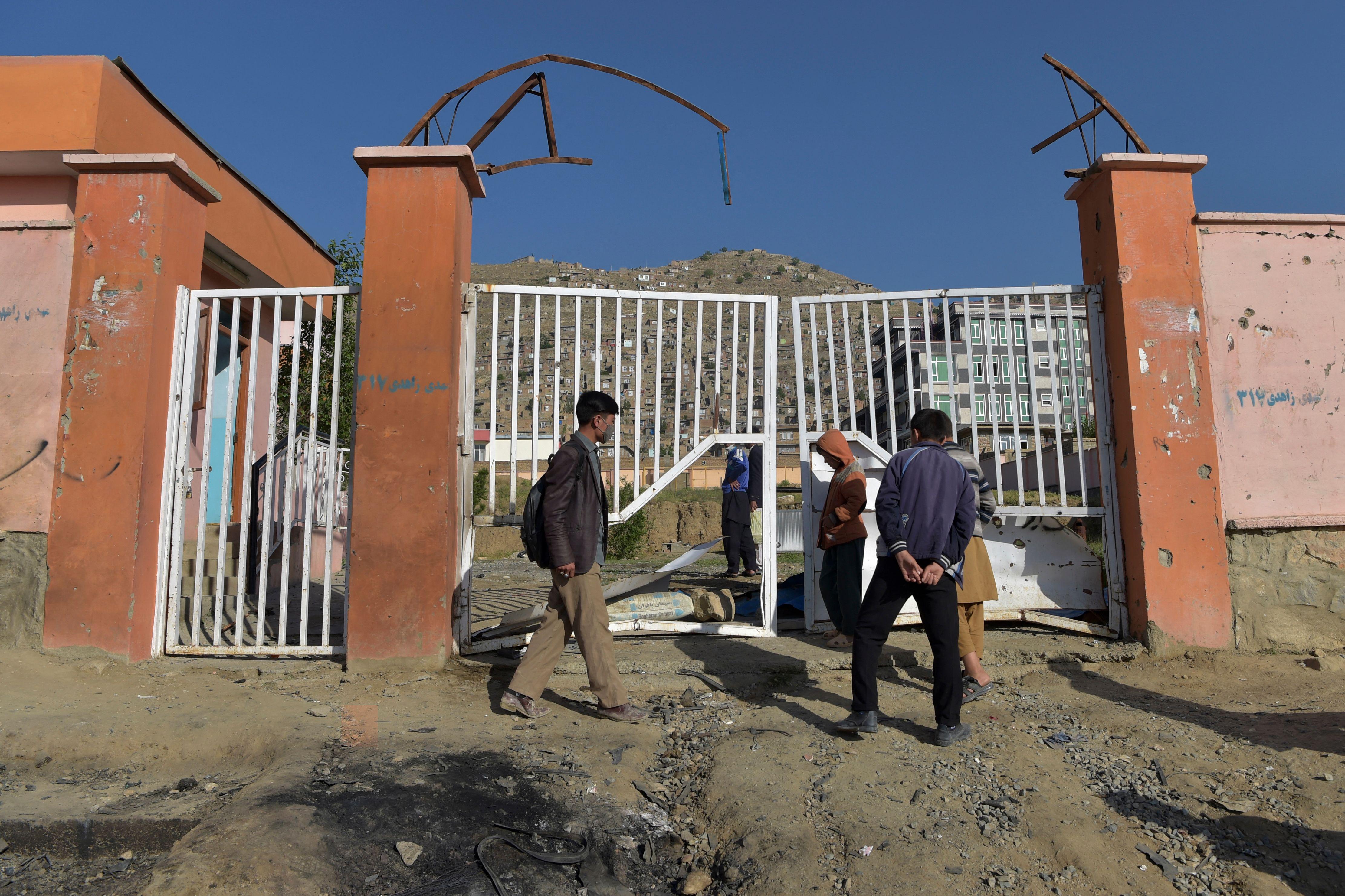 Onlookers stand near the site of yesterday's multiple blasts outside a girls' school in Dasht-e-Barchi on the outskirts of Kabul on May 9, 2021.
