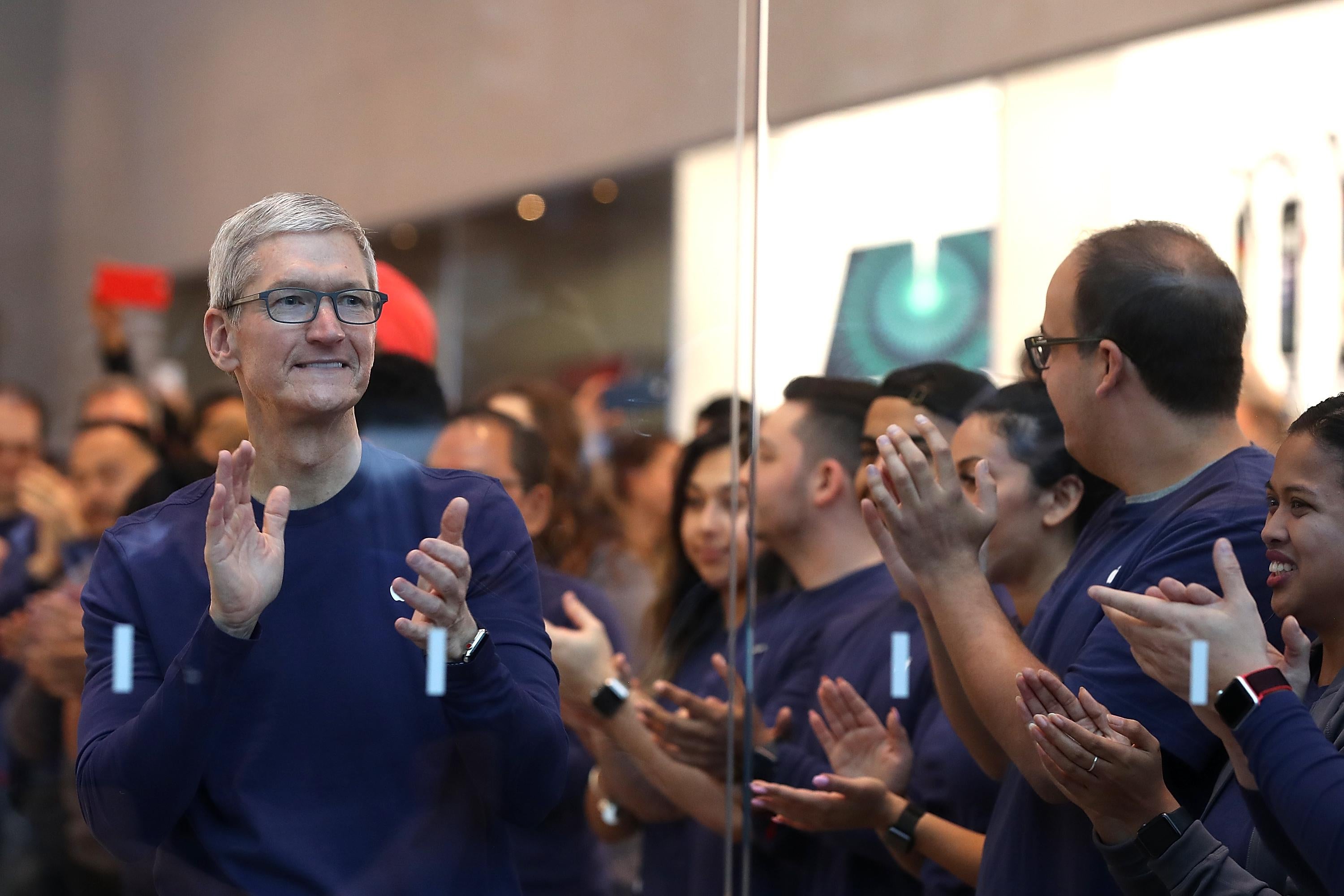 Tim Cook and others applaud inside an Apple store.