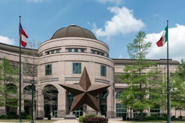 Exterior of the museum's central dome and rotunda with a large Lone Star sculpture, a Confederate States of America flag, and a Mexican flag out front