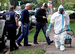 A man dressed in protective hazmat clothing leaves after treating the front porch and sidewalk of the apartment of Nina Pham, Oct. 12, 2014, in Dallas