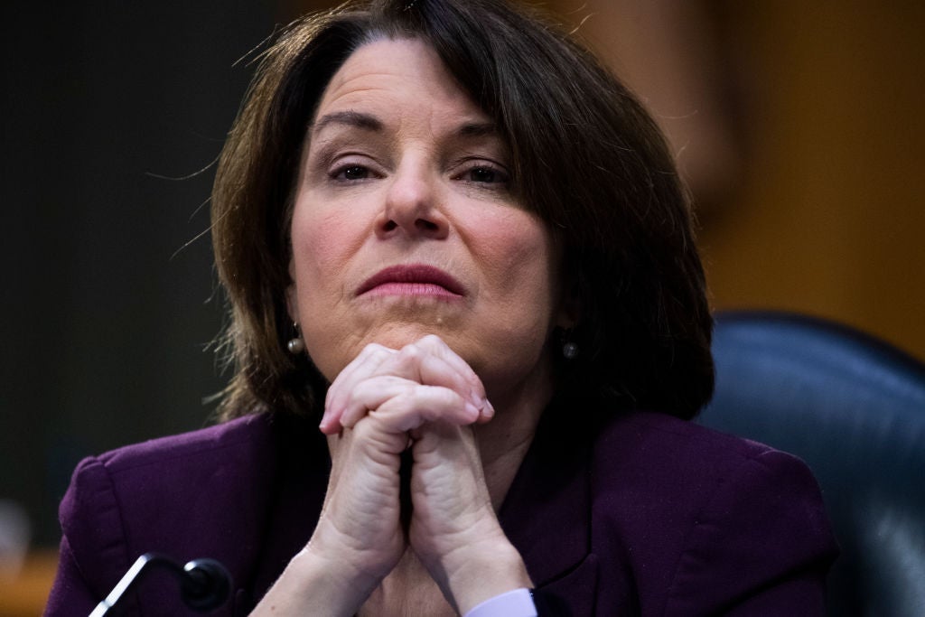 Klobuchar seated with her hands clasped under her chin.