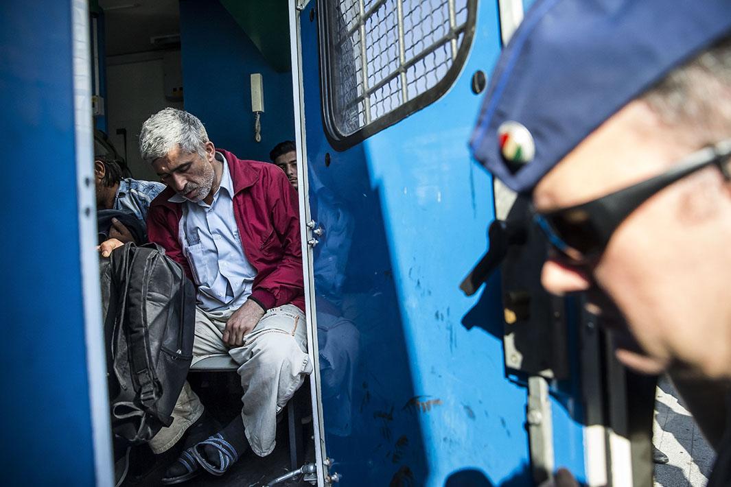 Refugees sit in a police vehicle in Budapest, Hungary, on Sept. 2, 2015
