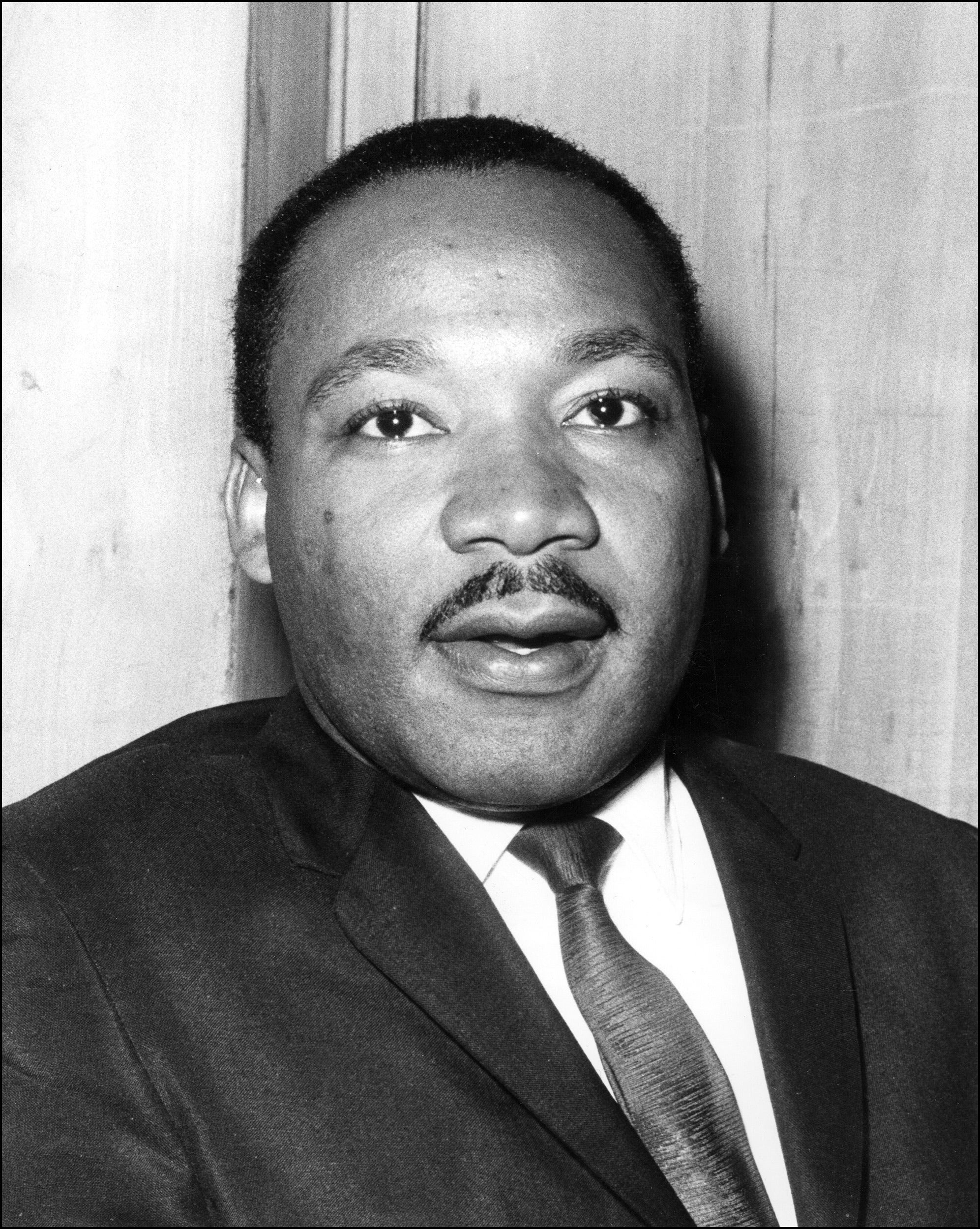 Archival image of MLK in a suit and tie, slightly smiling.
