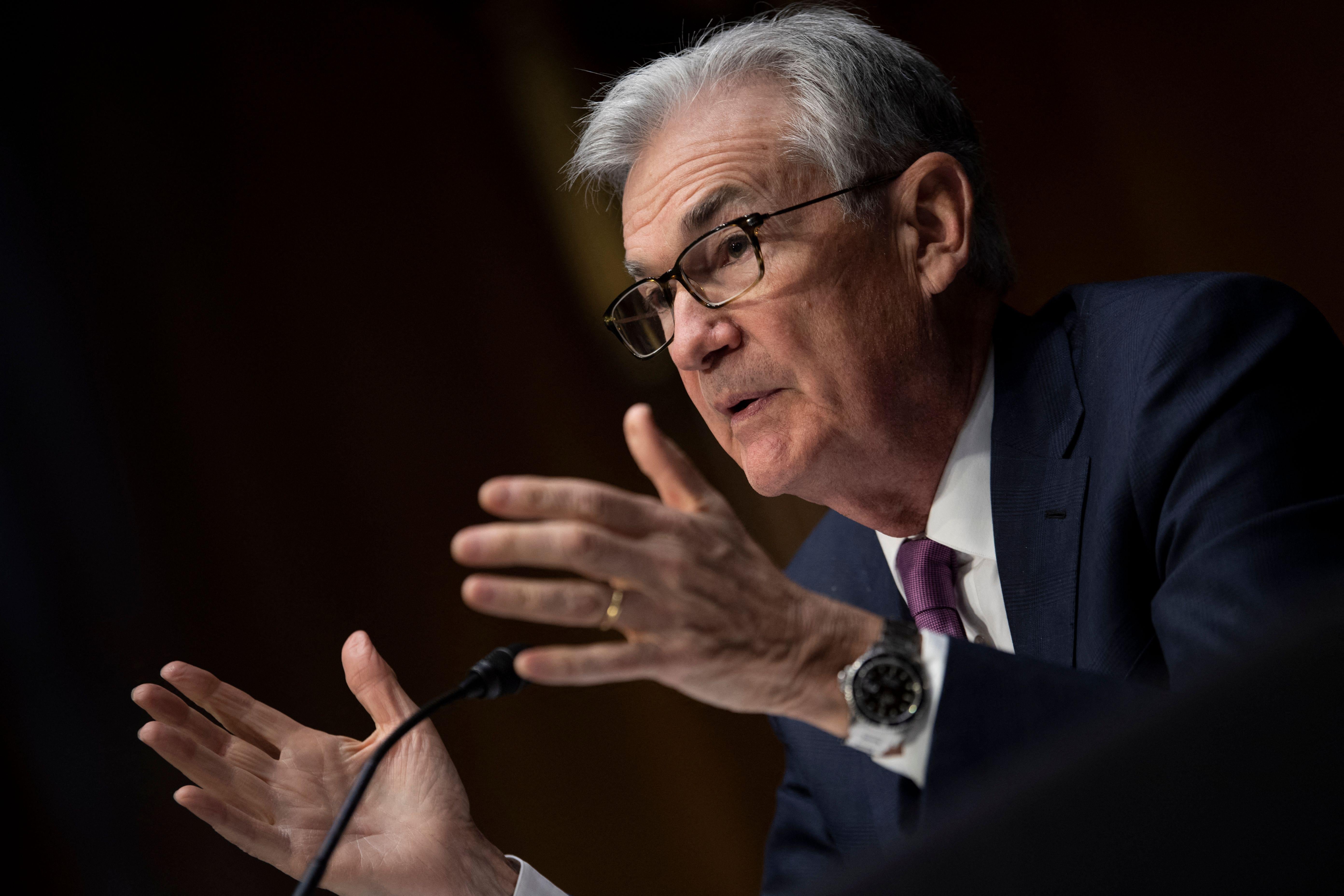 Jerome Powell gestures with both hands as he speaks seated in front of a mic