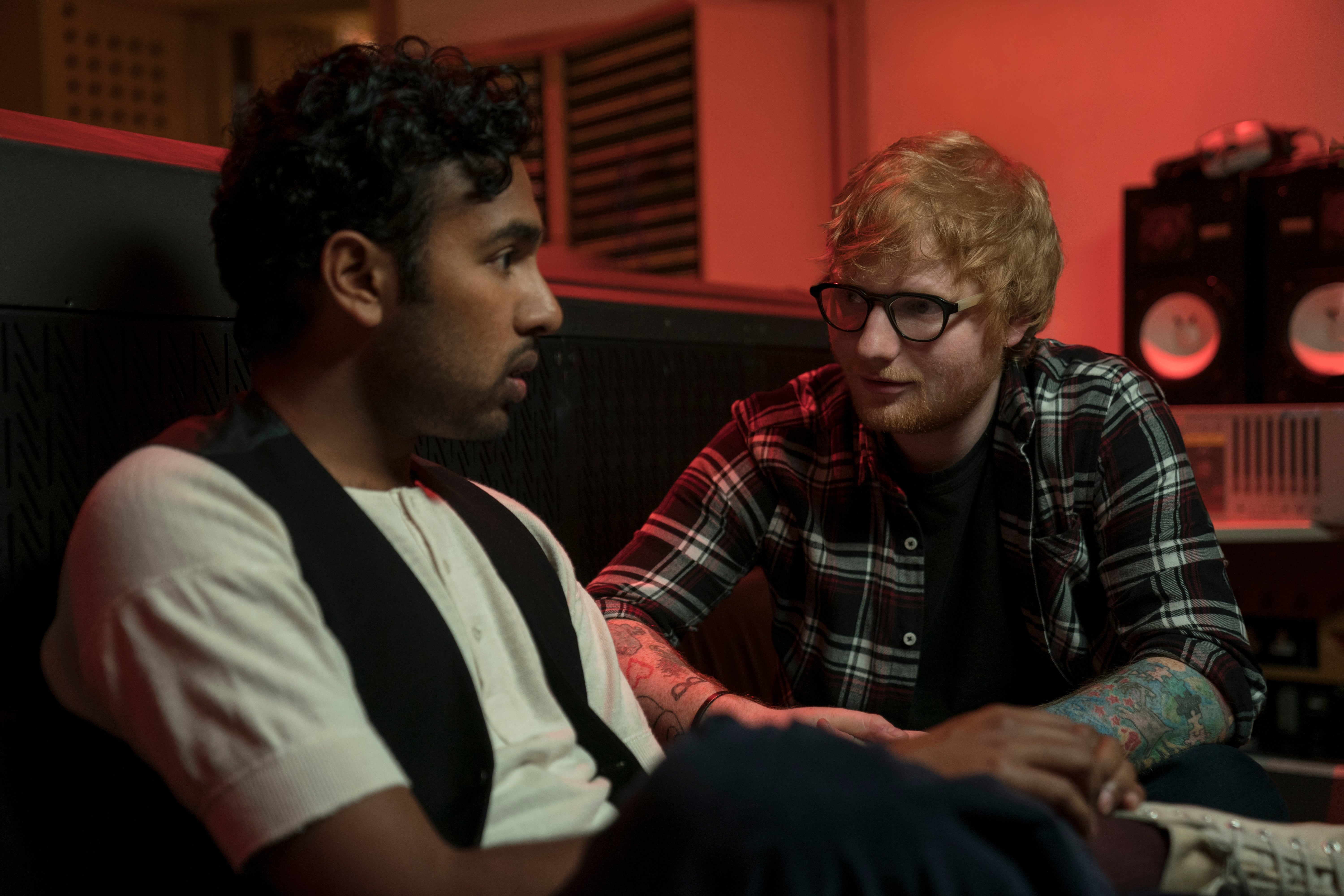 Hamish Patel and Ed Sheeran sit in a red-tinted room.
