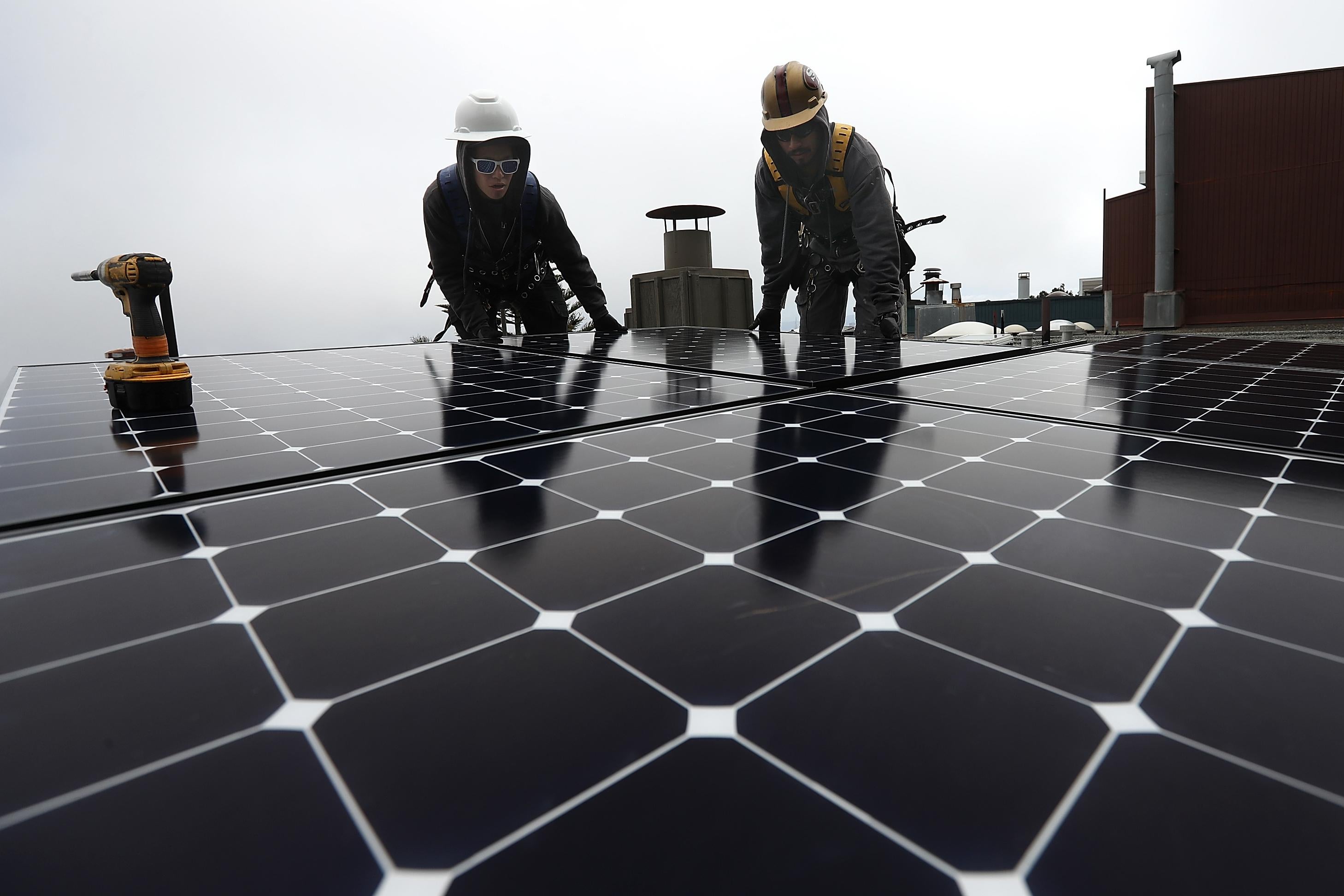 Workers of Luminalt, a solar panel company, install solar panels on the roof of a home on May 9, 2018 in San Francisco, California.