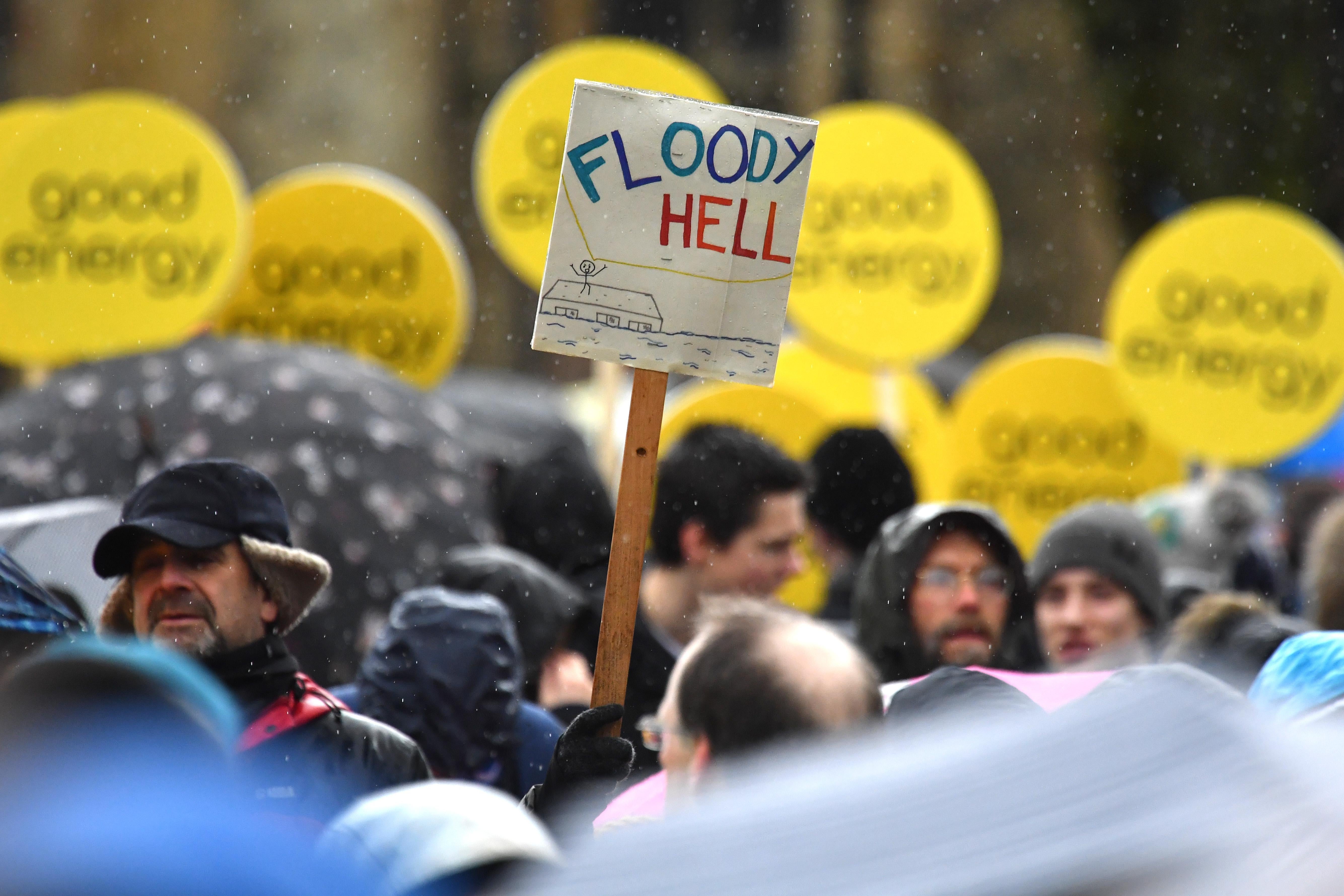 A crowd of protesters holding signs that say "Good energy" and one that says "Floody Hell"