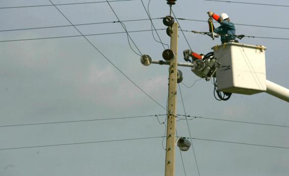 A utility worker repairs an electrical line 